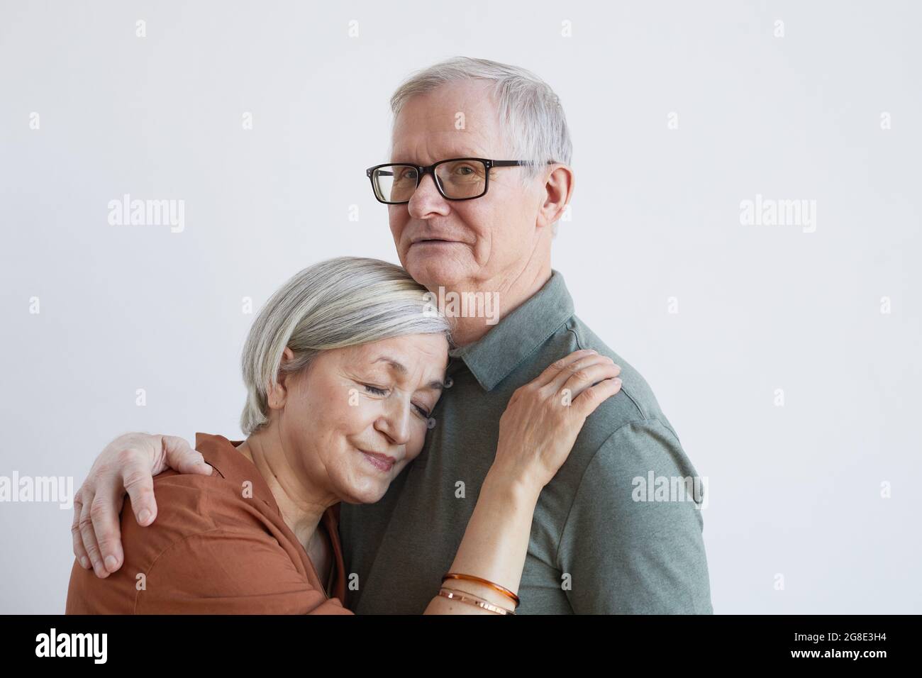 Portrait d'un couple expérimenté aimant qui s'embrasse et regarde l'appareil photo tout en se tenant sur fond blanc, espace de copie Banque D'Images