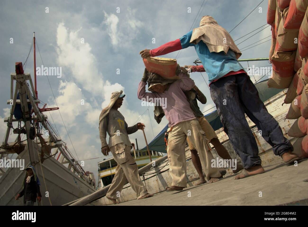 Travailleurs transportant des sacs de ciment sur le navire phinisi au port de Sunda Kelapa à Jakarta, Indonésie. Banque D'Images