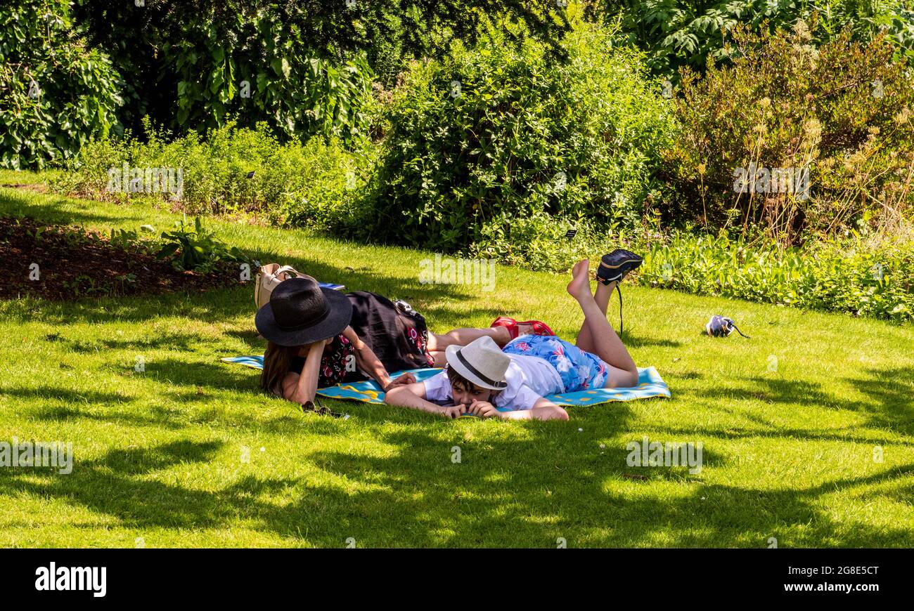 Mère et fils se détendant sur un tapis sur une pelouse dans le Chelsea Physic Garden à Londres. Banque D'Images