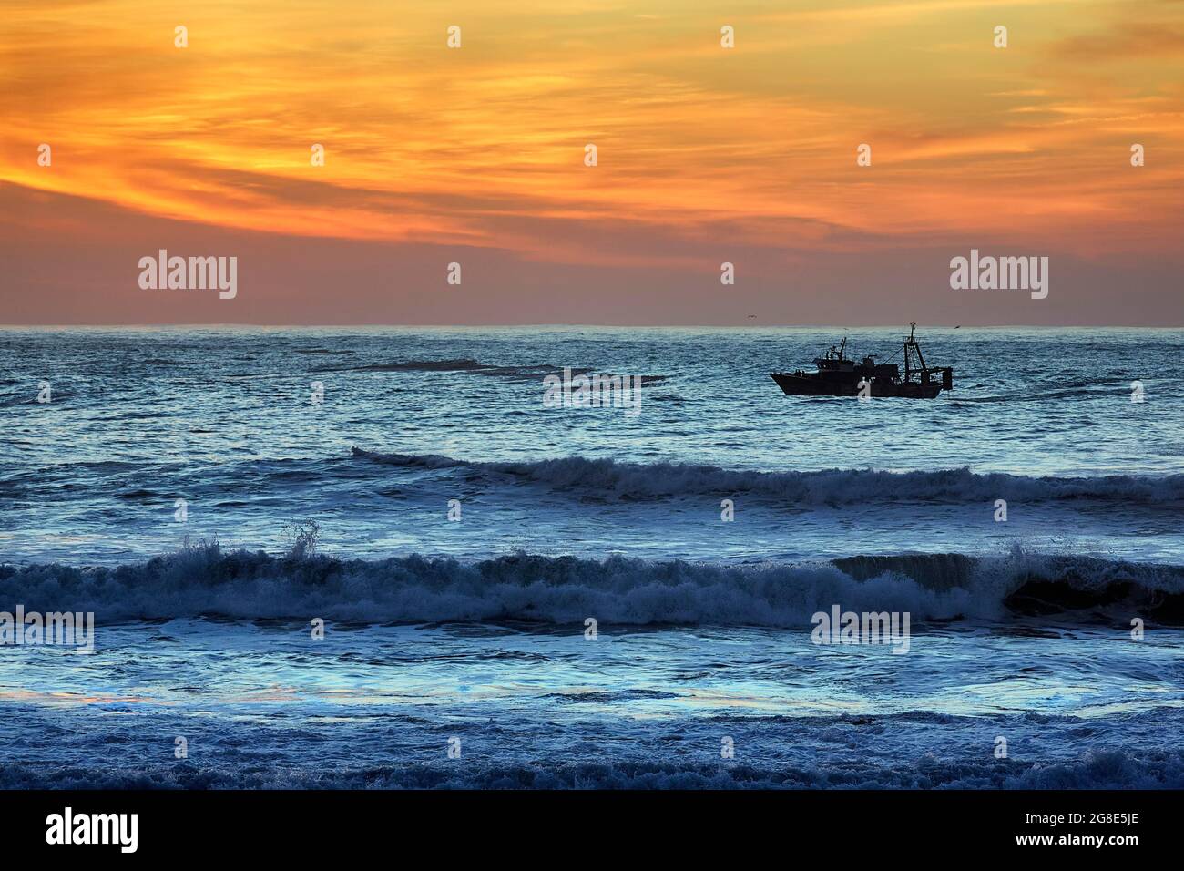 Bateau de pêche dans les vagues, heure bleue, côte Atlantique, Essaouira, Marrakech-Safi, Maroc Banque D'Images