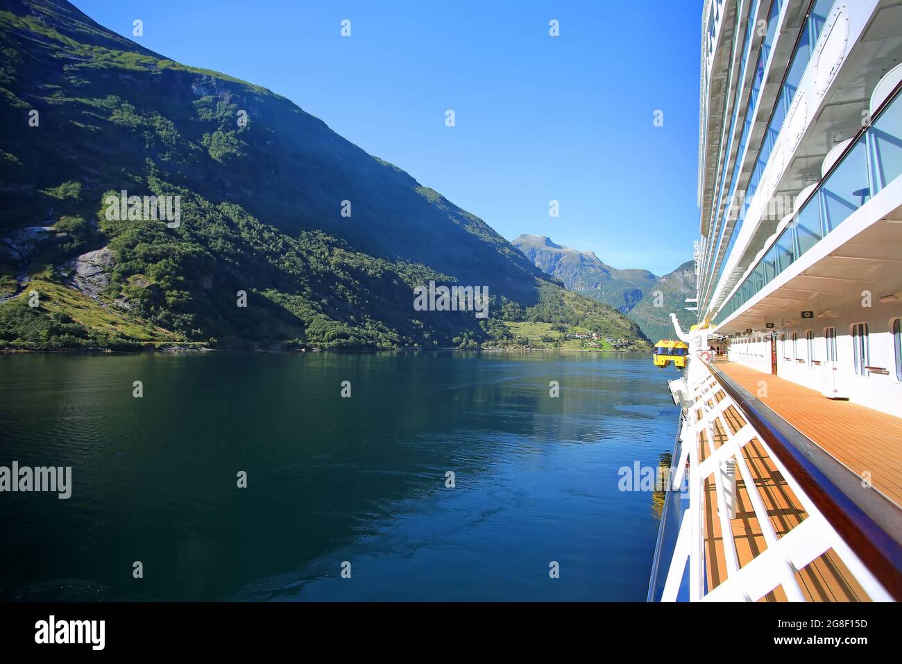 Bateau de croisière abaissant tendre dans l'eau lors d'une belle journée d'été. Réflexions des montagnes dans le fjord. Ville de Geiranger, Norvège Banque D'Images