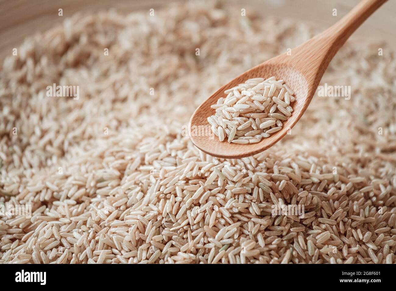 Riz brun dans une cuillère en bois ou en bambou Banque D'Images