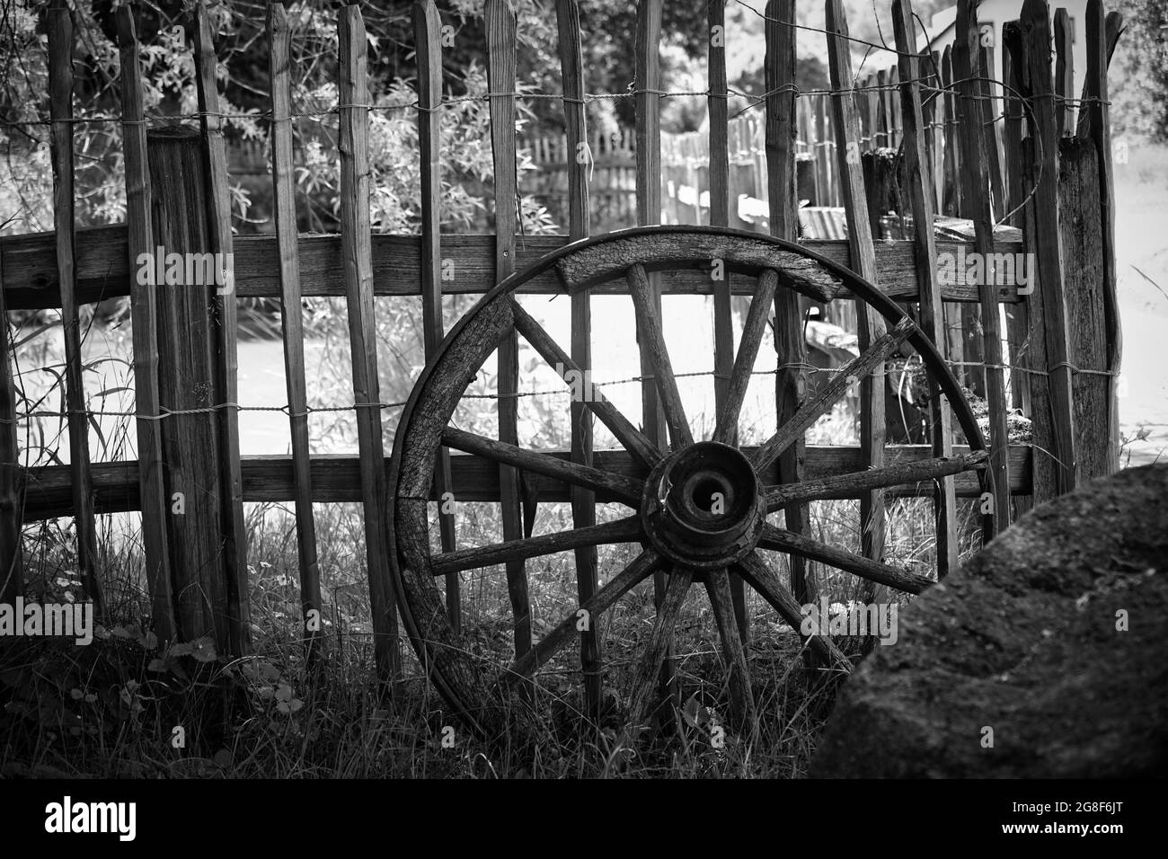 Ancienne roue de chariot penchée sur une clôture en bois Banque D'Images