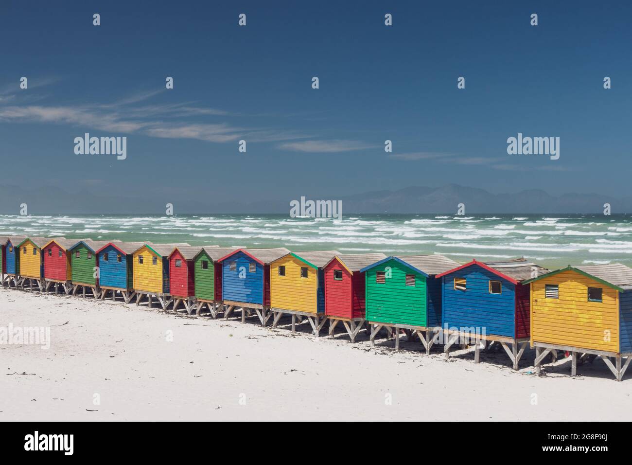 Célèbres maisons de plage colorées à Muizenberg près de Cape Town, Afrique du Sud avec des montagnes Hottentots Holland dans le fond contre le ciel bleu Banque D'Images