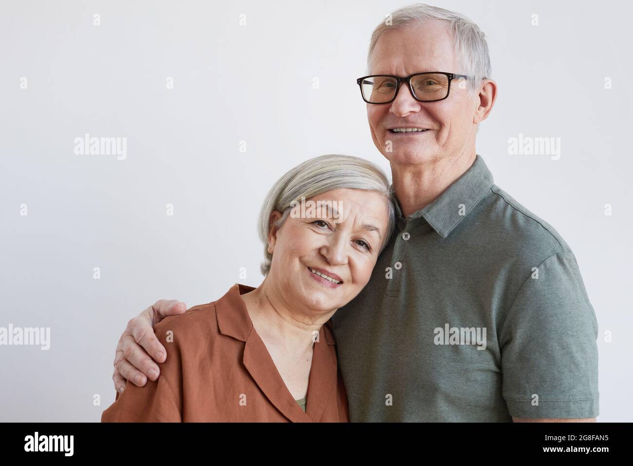 Portrait d'un couple senior heureux qui s'embrasse et regarde l'appareil photo tout en se tenant sur fond blanc, espace de copie Banque D'Images