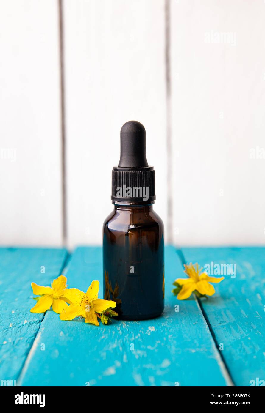 Hypericum perforatum connu sous le nom de teinture de millepertuis ou bouteille d'huile avec fleurs végétales pour la décoration sur fond de bois blanc. Banque D'Images