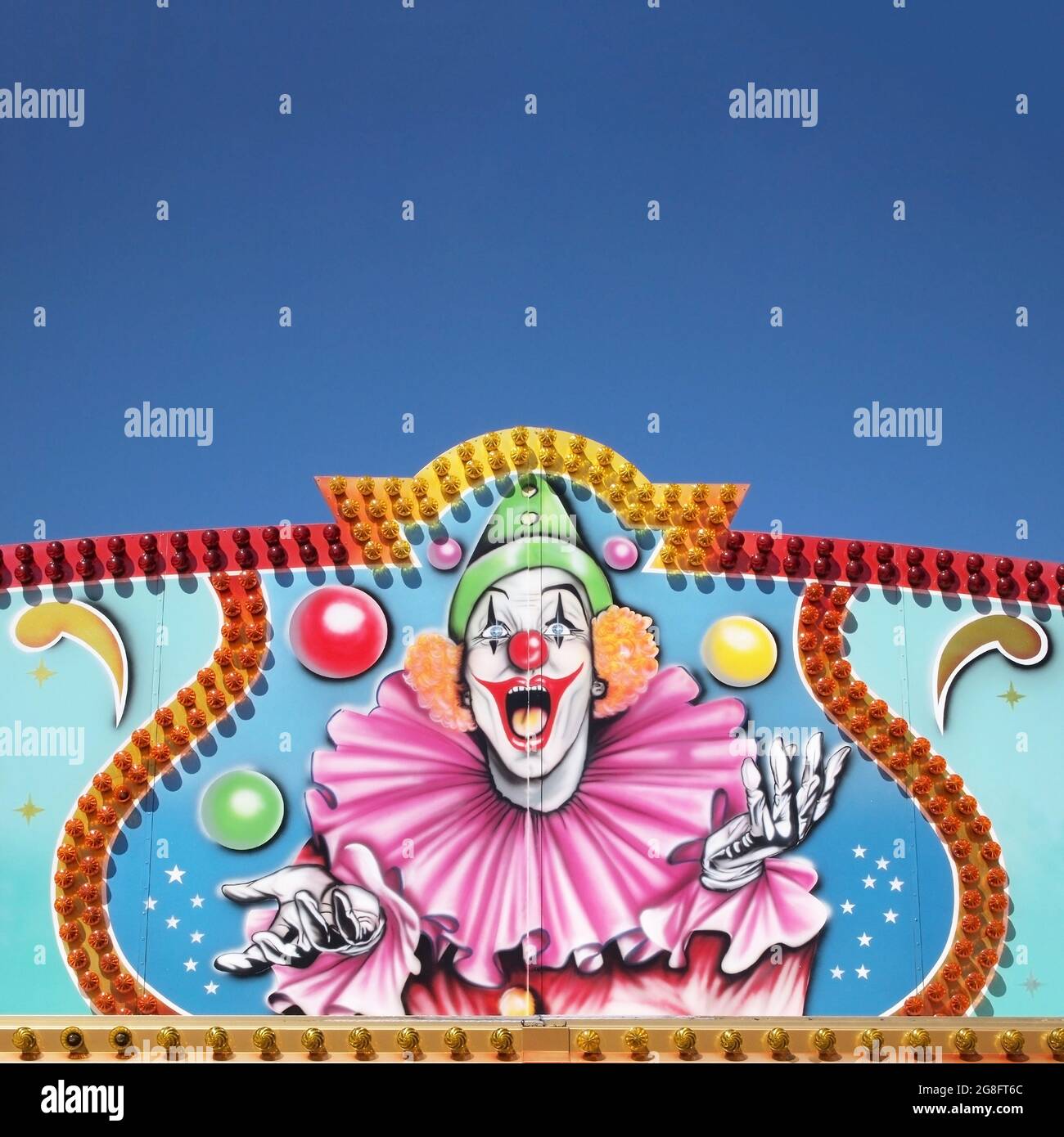 Gros plan d'un clown de cirque peint sur le mur sous un ciel bleu Banque D'Images