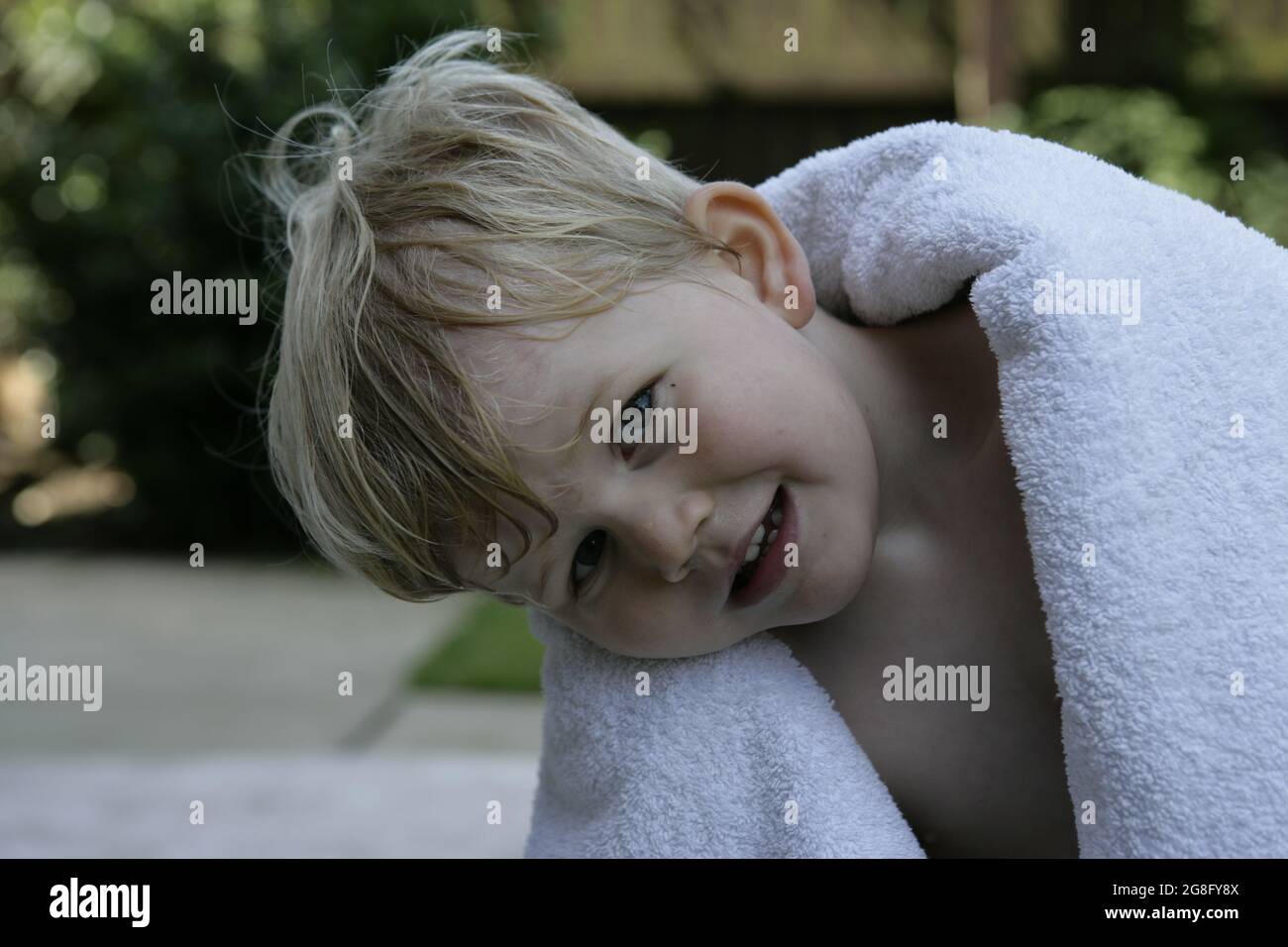 Jardin d'été extérieur portrait d'un jeune enfant avec cheveux blonds enveloppés d'une serviette Banque D'Images