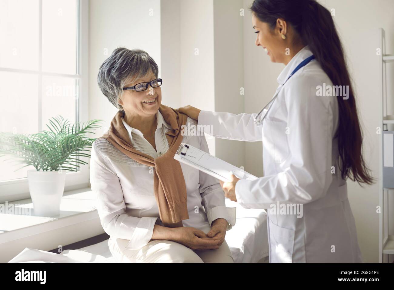 Femme médecin avec une patiente âgée heureuse qui parle dans le bureau de l'hôpital Banque D'Images