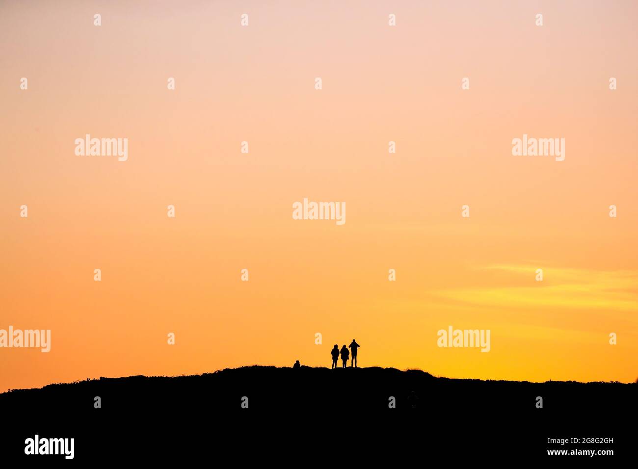 Les gens regardent le coucher du soleil sur le sommet de la montagne Cavehill, surplombant Belfast en Irlande du Nord, le plus long jour de l'année pendant le solstice d'été. Banque D'Images