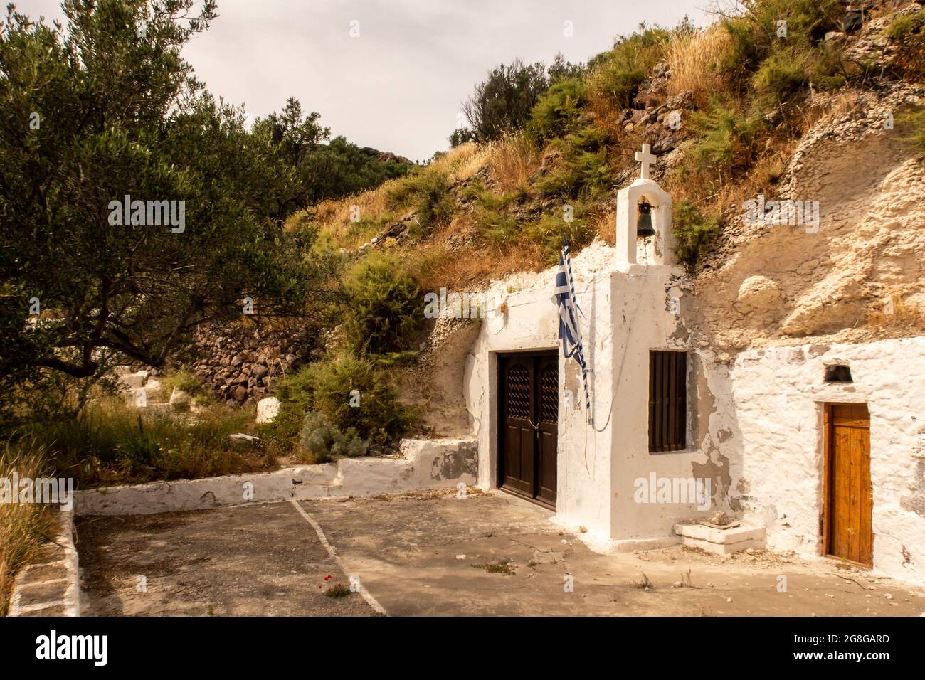 Ancienne petite église chrétienne blanchie à la chaux construite dans un rocher sur une colline sur l'île de Milos près de la ville de Trypiti avec des plantes vertes autour, Cyclades, Grèce. Banque D'Images