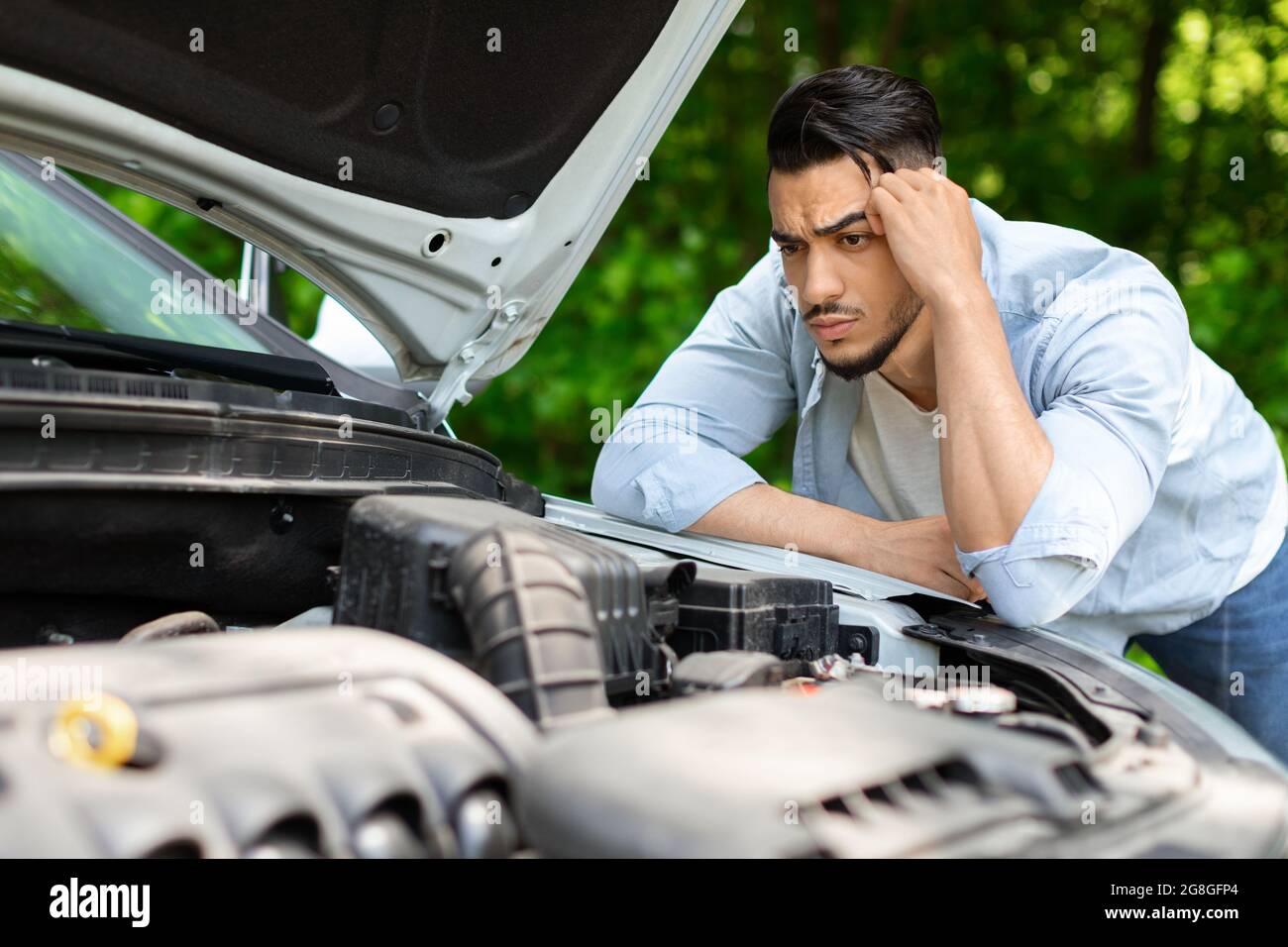 Perplexe, homme arabe pendu sur le capot de la voiture Banque D'Images