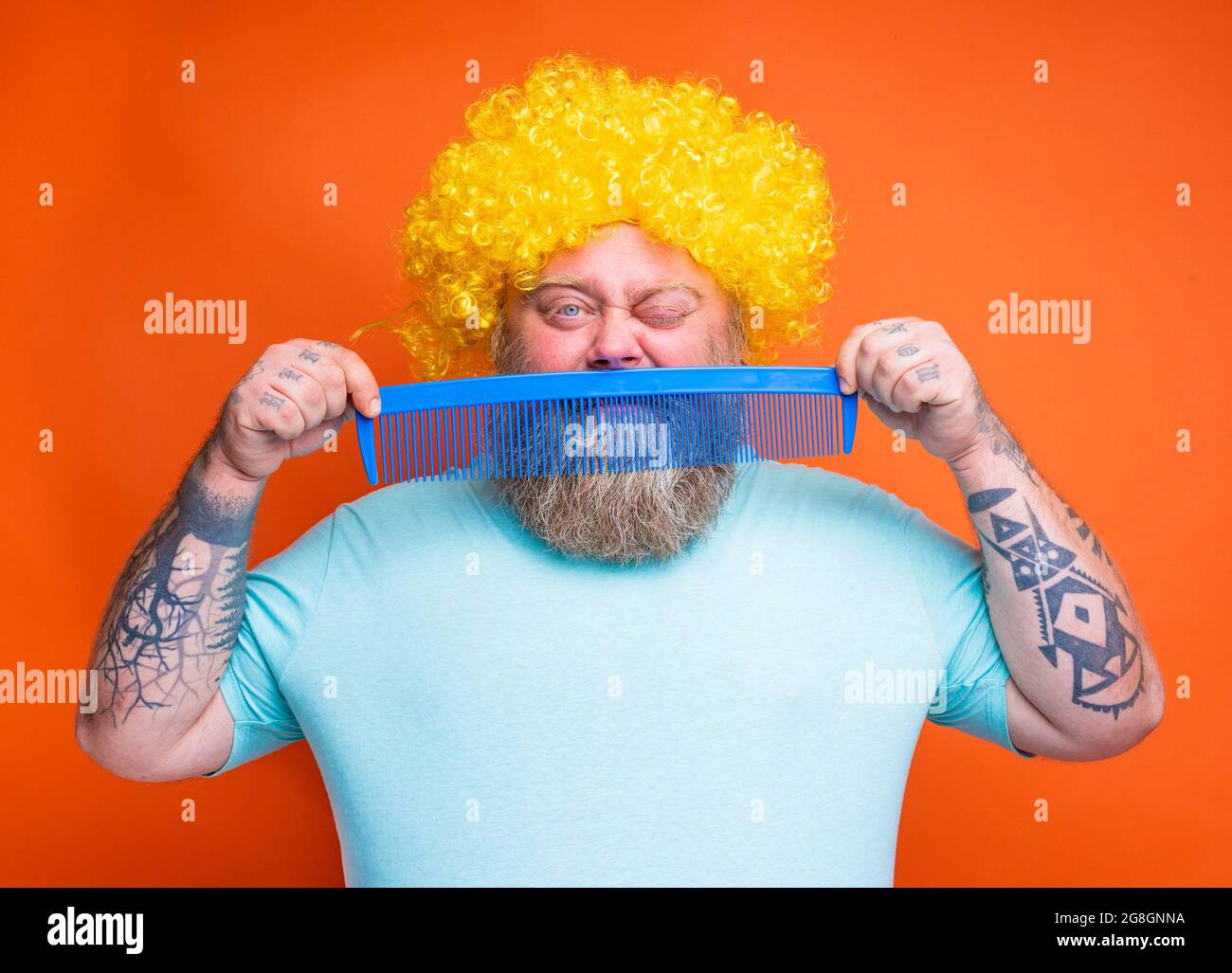 Gros douter homme avec la barbe, tatouages et lunettes de soleil se peignes  avec un peigne géant Photo Stock - Alamy