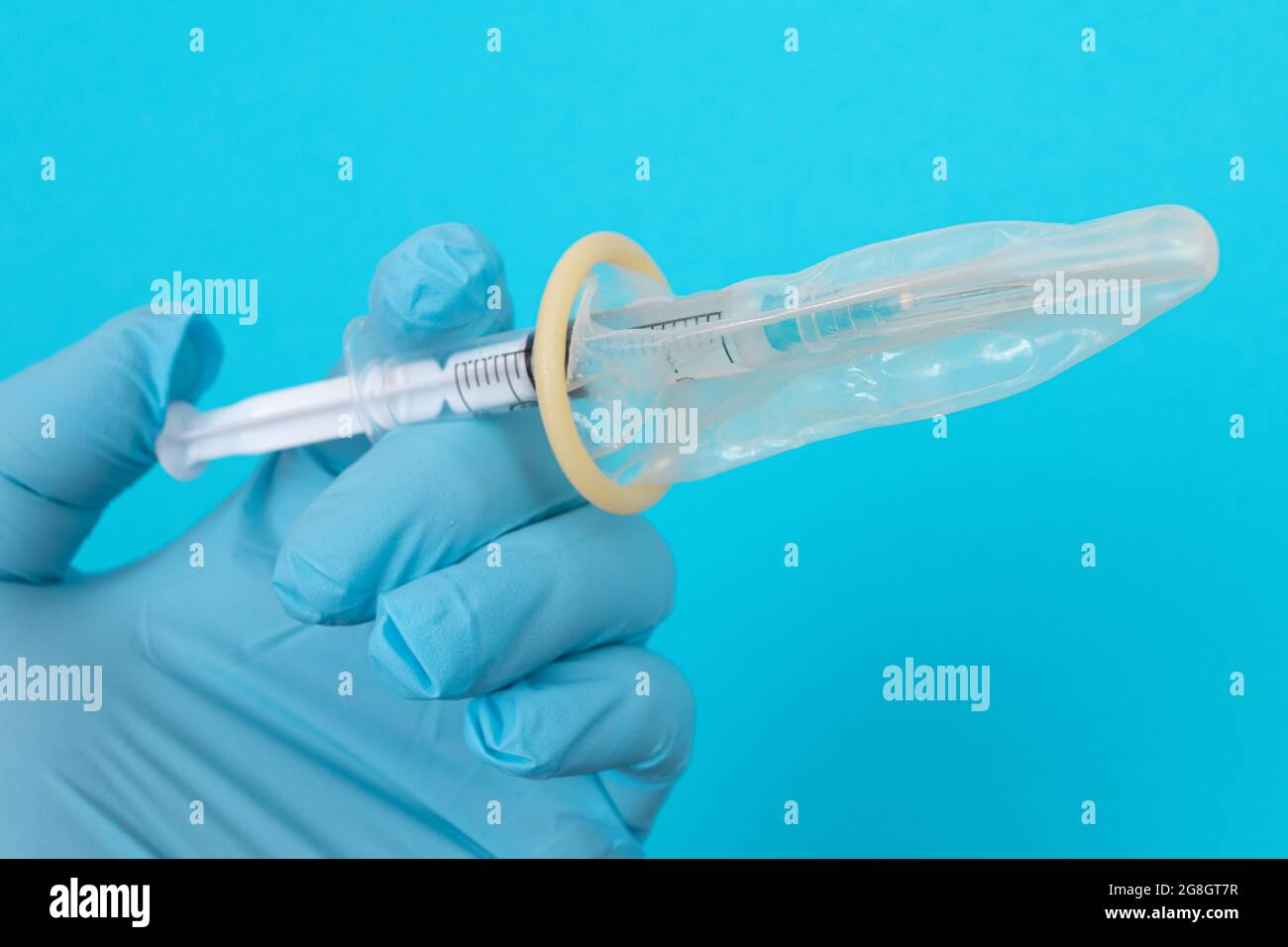 Vaccin sûr, anti-vaccin concept - seringue dans un condom tient dans une main avec un gant médical. Méfiance à l'égard de la vaccination. Immunité naturelle. Scepticisme à propos du vaccin. Liberté et droits de l'homme Banque D'Images