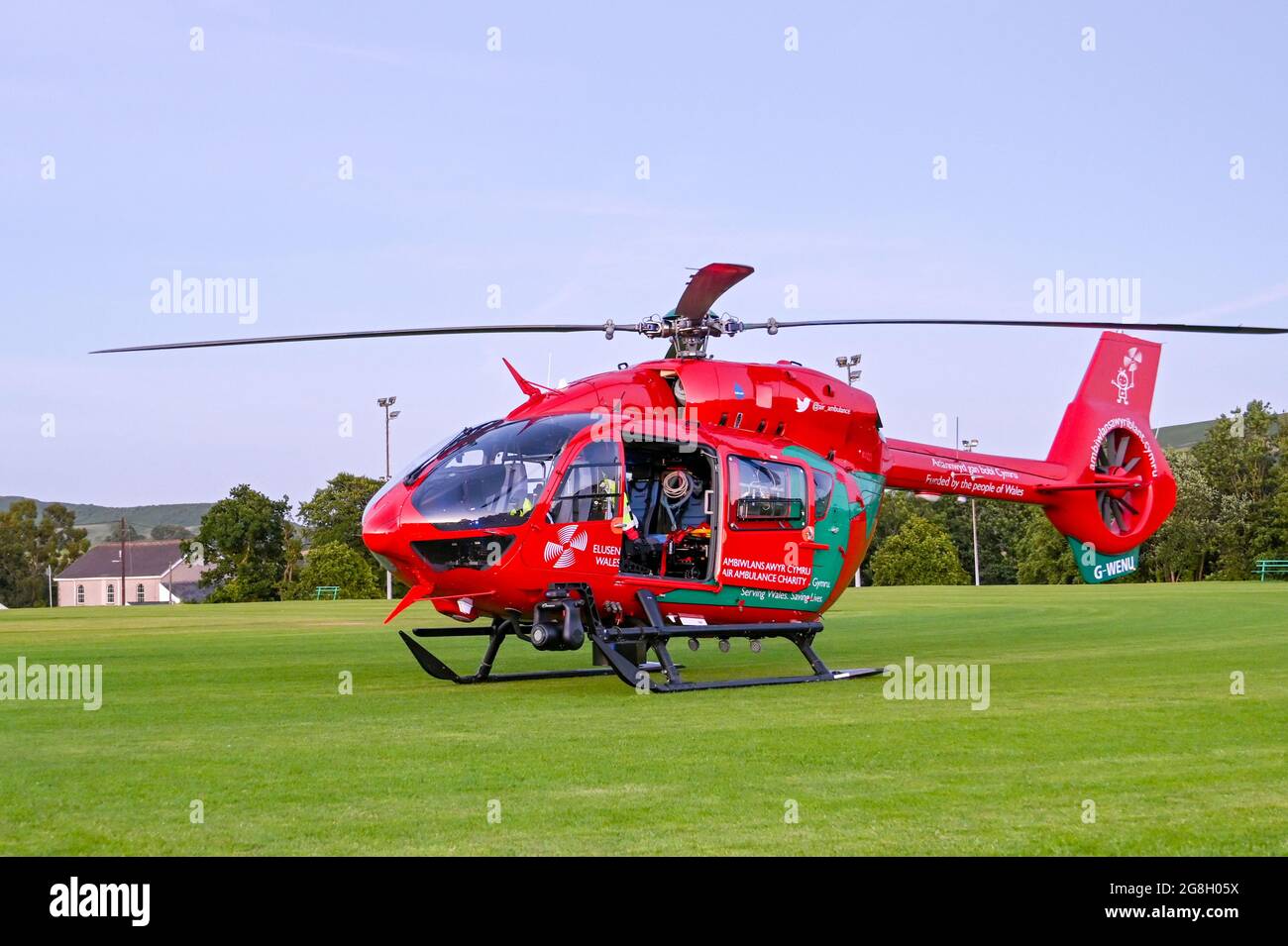 Pontypridd, pays de Galles - juillet 2021 : Airbus hélicoptère de l'ambulance aérienne du pays de Galles après l'atterrissage sur un terrain de cricket au crépuscule. Banque D'Images