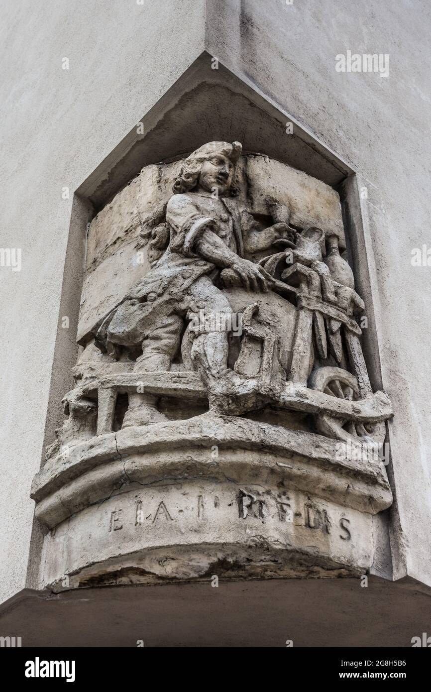 Vieille sculpture en pierre au coin de la rue parisienne représentant une roue de potier et potier - Paris, France. Banque D'Images