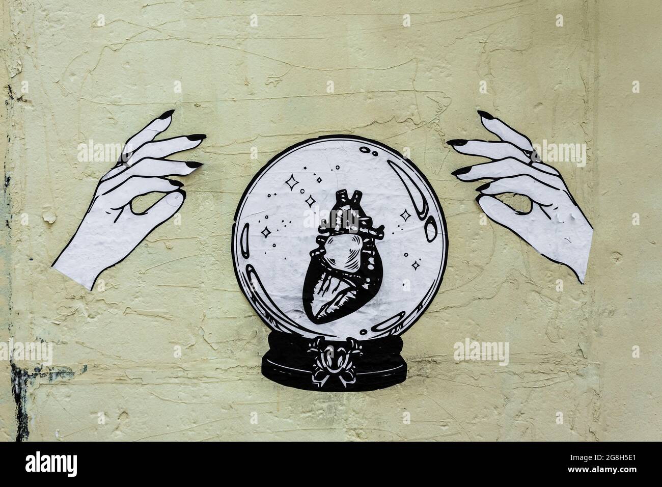 Papier graphique des mains et des cristaux boule collée sur le mur - Paris, France. Banque D'Images