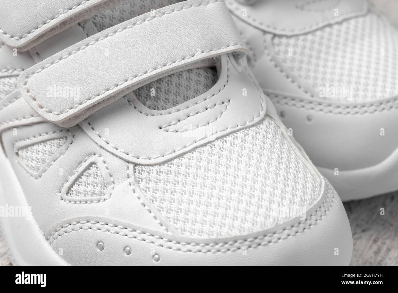 Macro photographie des sneakers blanches. Deux chaussures blanches pour enfants avec attaches Velcro pour le confort des chaussures pour enfants, vue du dessus Banque D'Images