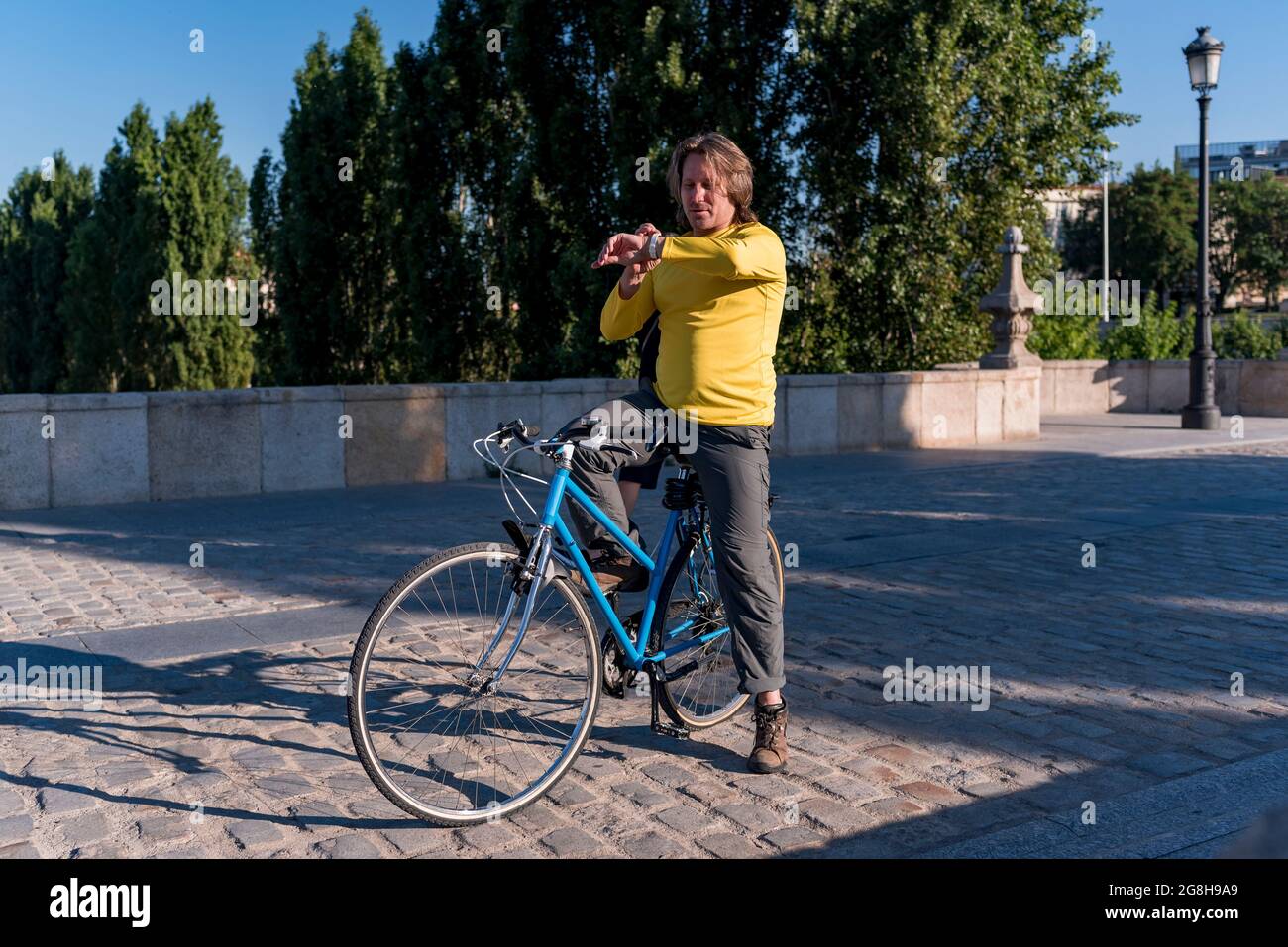 Homme caucasien avec horloge et vélo dans la ville Banque D'Images