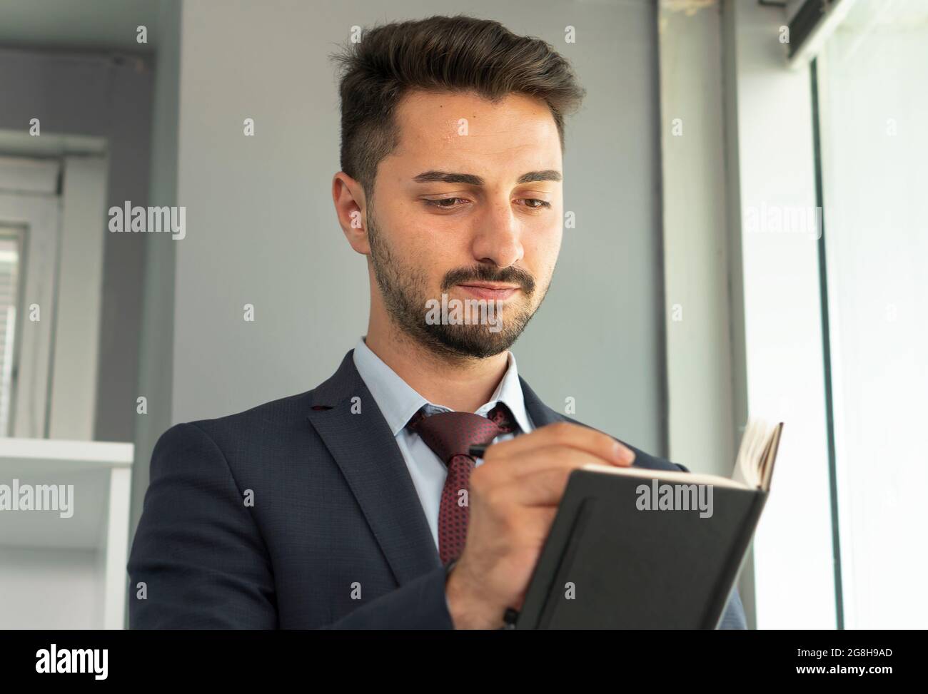 Portrait de la personne d'affaires concentrée en costume écrivant ses plans au bloc-notes. Banque D'Images
