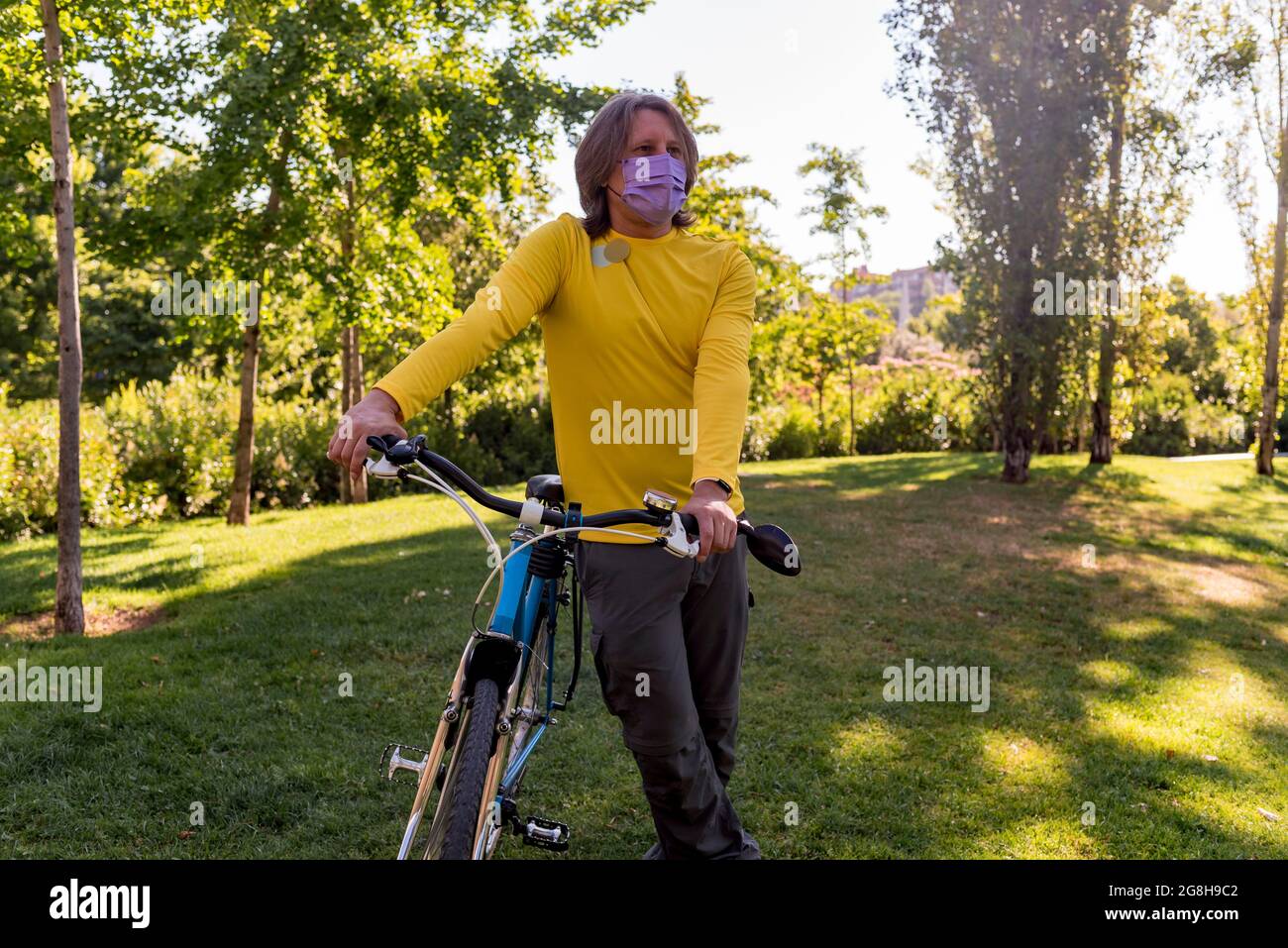 Homme portant un masque dans le parc avec sa bicyclette Banque D'Images