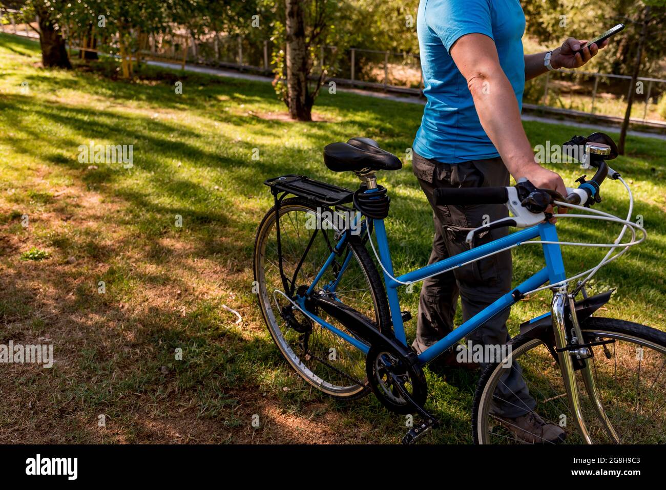 Homme méconnaissable marchant dans le parc avec son vélo Banque D'Images