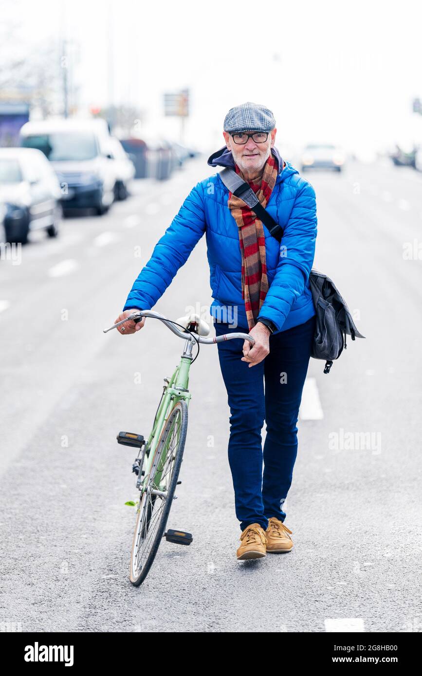Homme de haut niveau à vélo dans la rue de la ville tenant un sac à main  Photo Stock - Alamy
