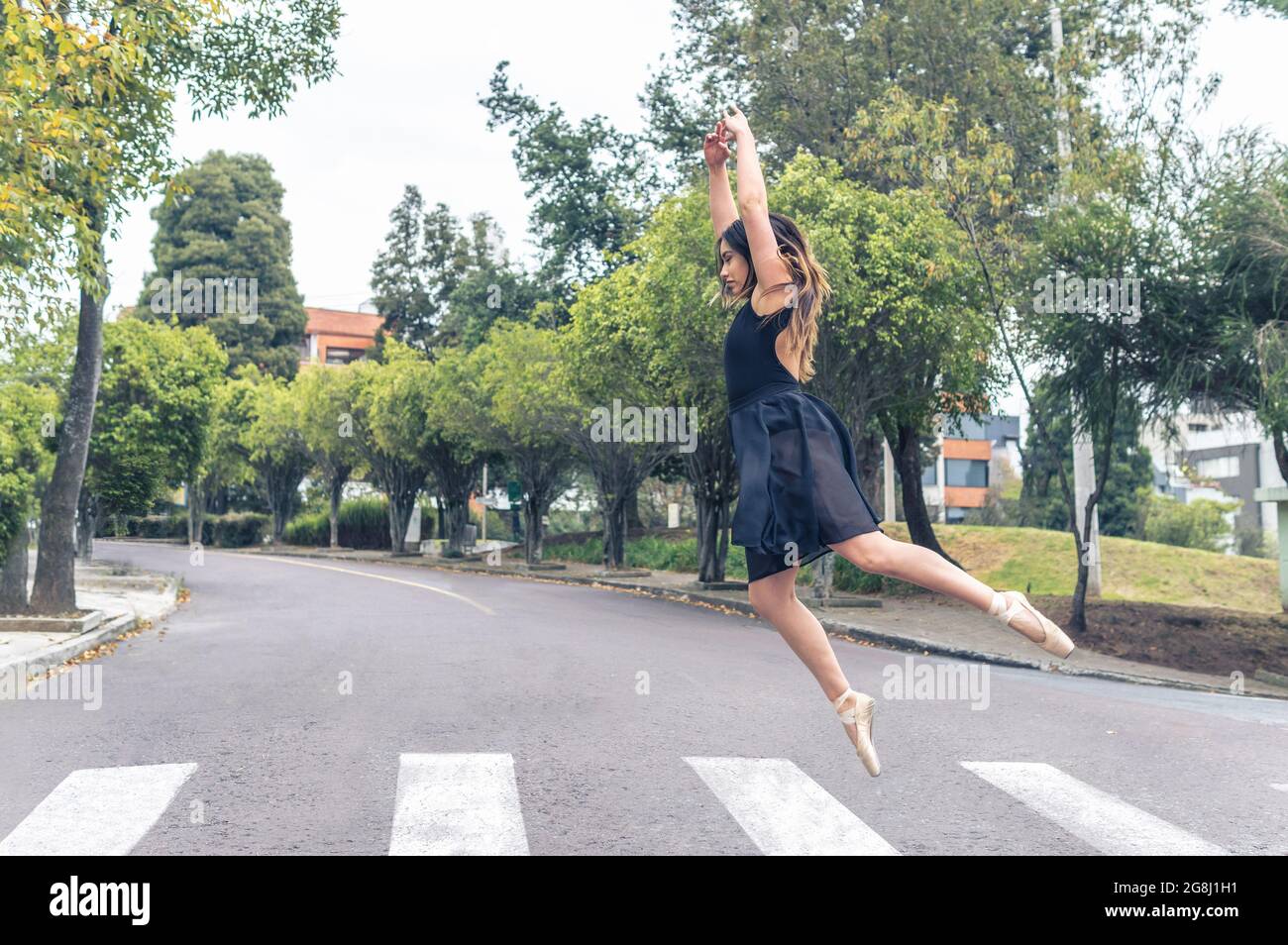 danseuse sautant les bras au-dessus d'une traversée piétonne dans la rue Banque D'Images