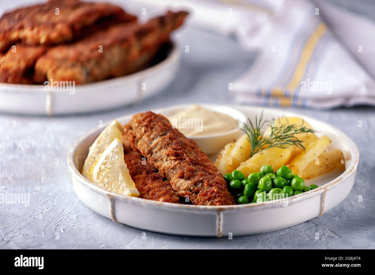 Poisson frit avec des pois verts, du citron et des pommes de terre frites Banque D'Images