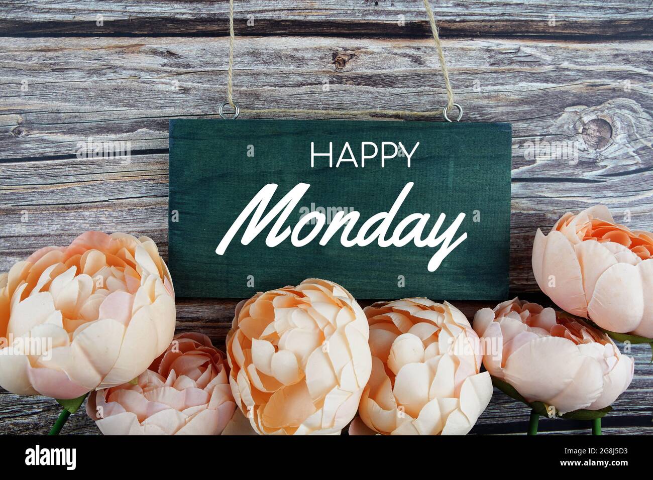 Texte typographique de Happy Monday avec bouquet de fleurs oranges sur fond en bois Banque D'Images