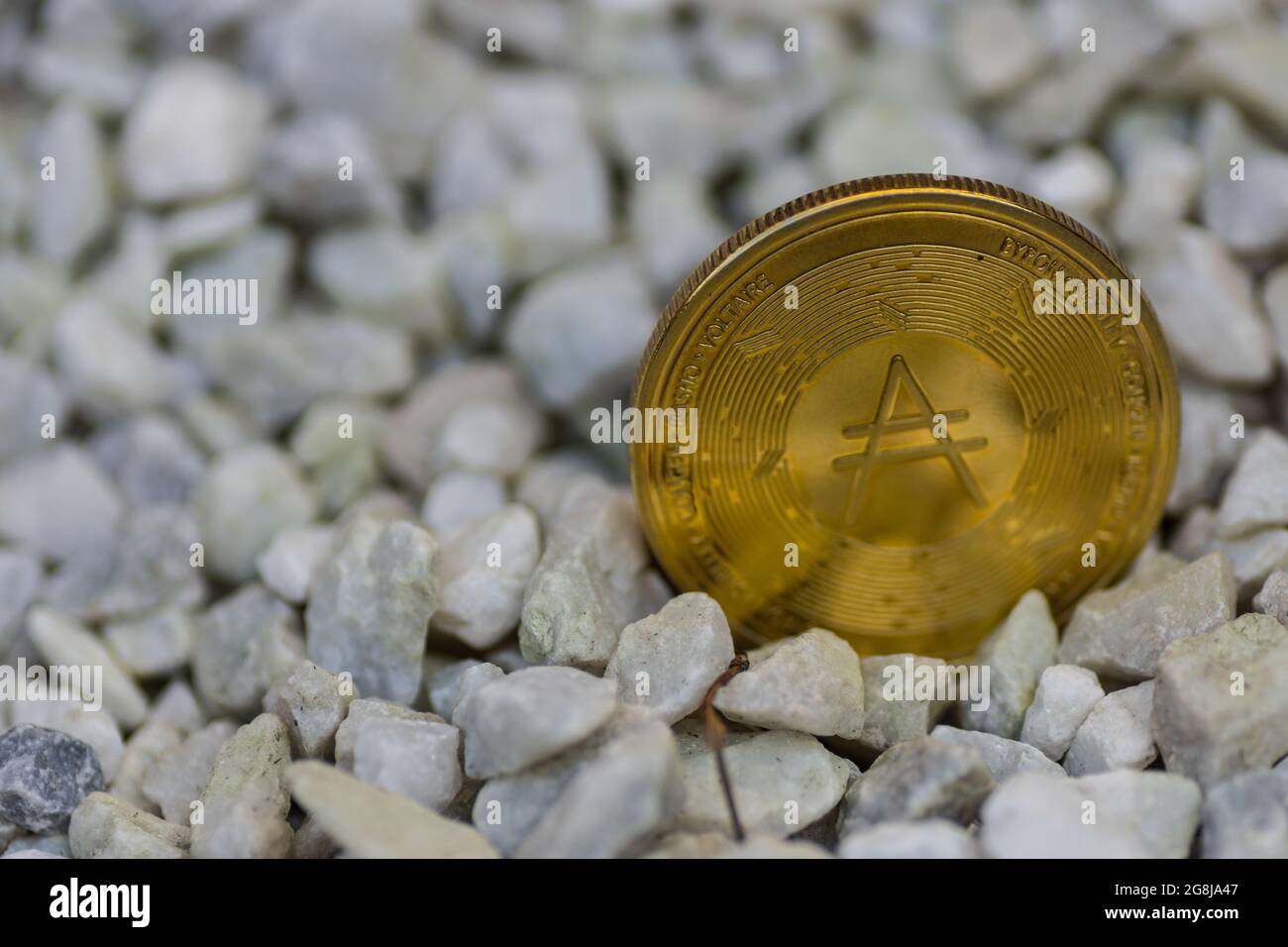 une seule pièce de monnaie ada dorée brillante de la monnaie de cardano debout dans un gravier avant droit Banque D'Images
