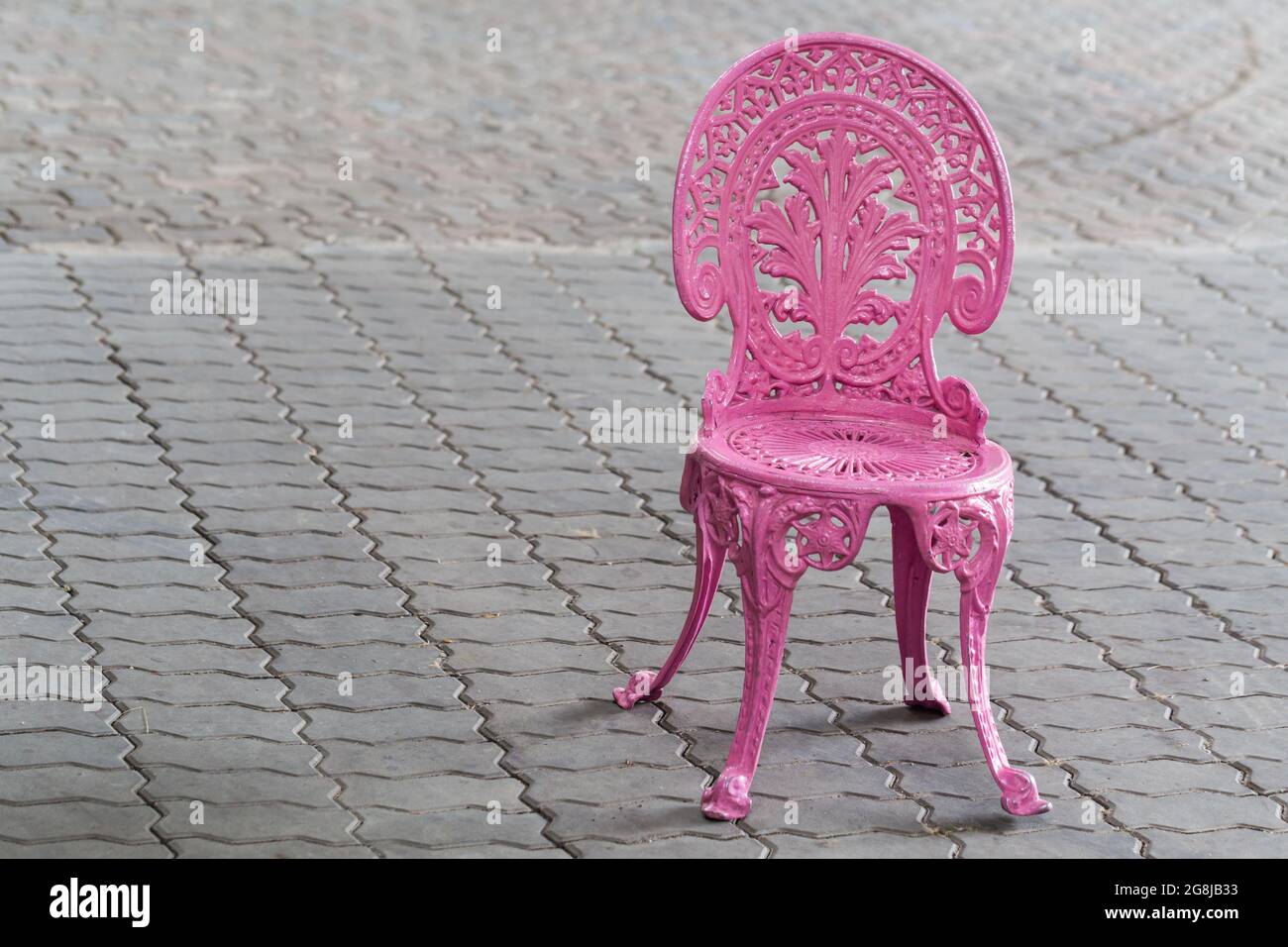 Chaise vintage en métal rose sur un sol en brique Banque D'Images