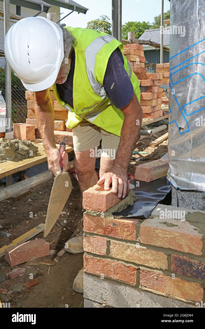 Une couche de brique construit le mur extérieur d'un nouveau bungalow à Surrey, au Royaume-Uni. Montre un échafaudage chargé de briques d'argile traditionnelles. Banque D'Images