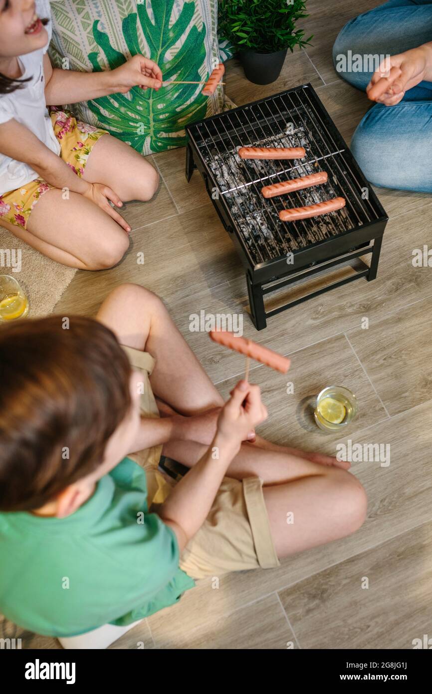 Vue de dessus du barbecue familial méconnu et de manger des saucisses sur le barbecue Banque D'Images