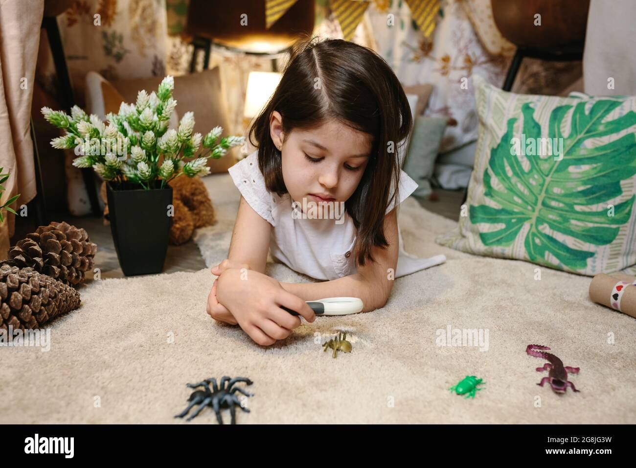 Fille jouant observant les insectes de jouet avec une loupe Banque D'Images