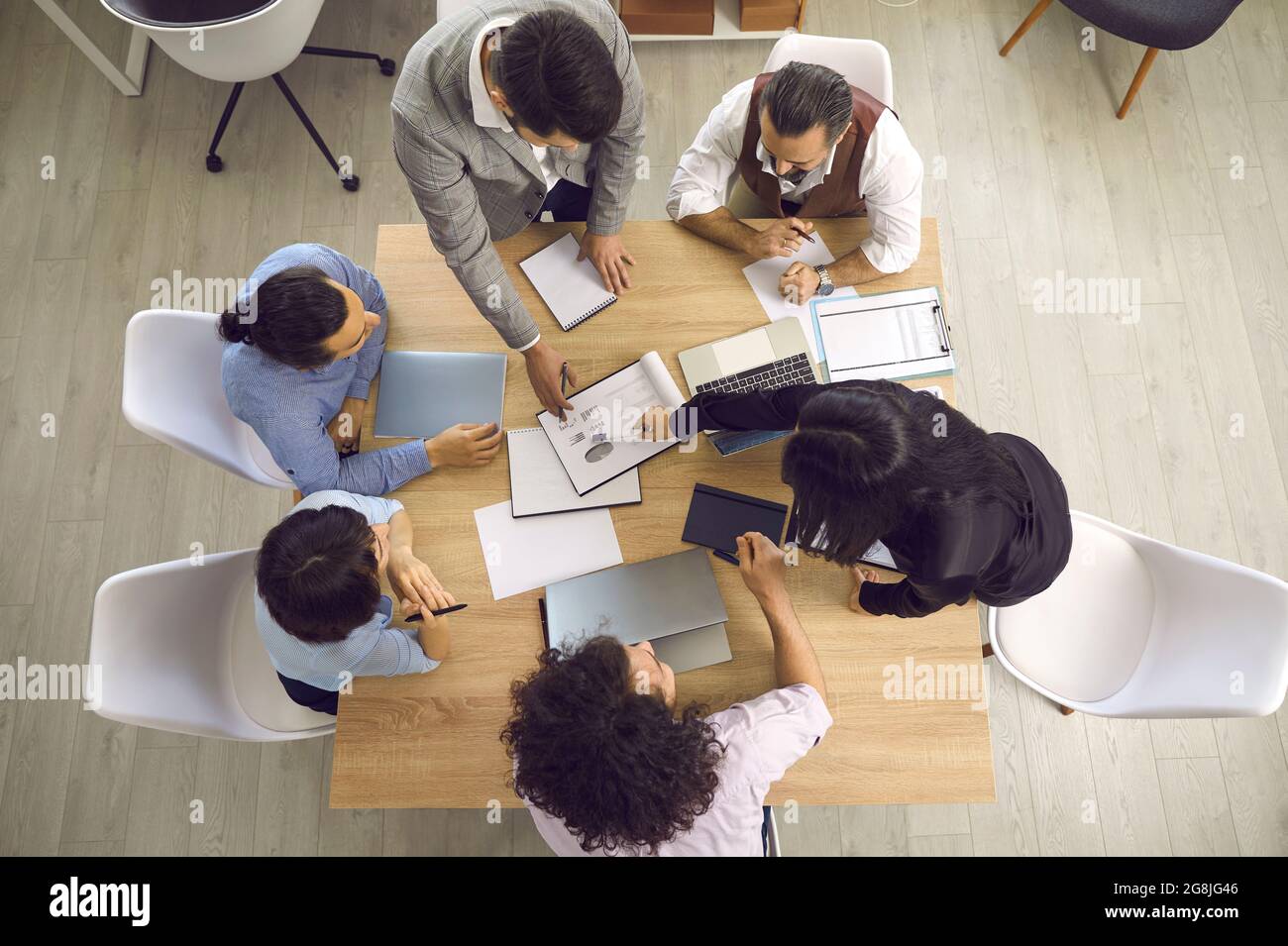 Vue de dessus des hommes d'affaires travaillant avec des ordinateurs portables et des documents assis à un bureau. Banque D'Images