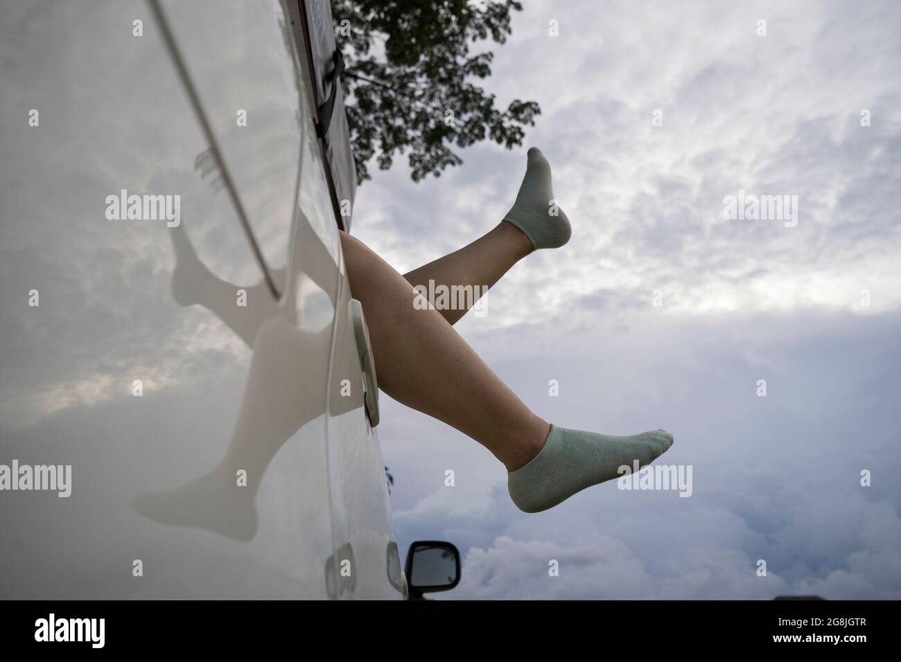 Pieds d'une fille asiatique en chaussettes chaudes de la fenêtre d'une voiture. Un petit voyage de vacances. Banque D'Images
