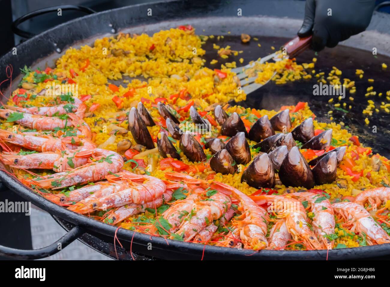 Paella cuite aux crevettes, musse, riz dans une immense casserole au festival de la nourriture de rue Banque D'Images