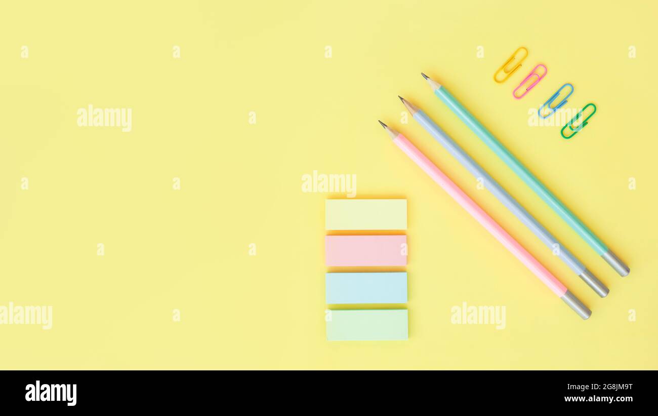 fournitures de bureau sur fond jaune avec espace de copie. Crayons graphite, trombones et notes adhésives Banque D'Images