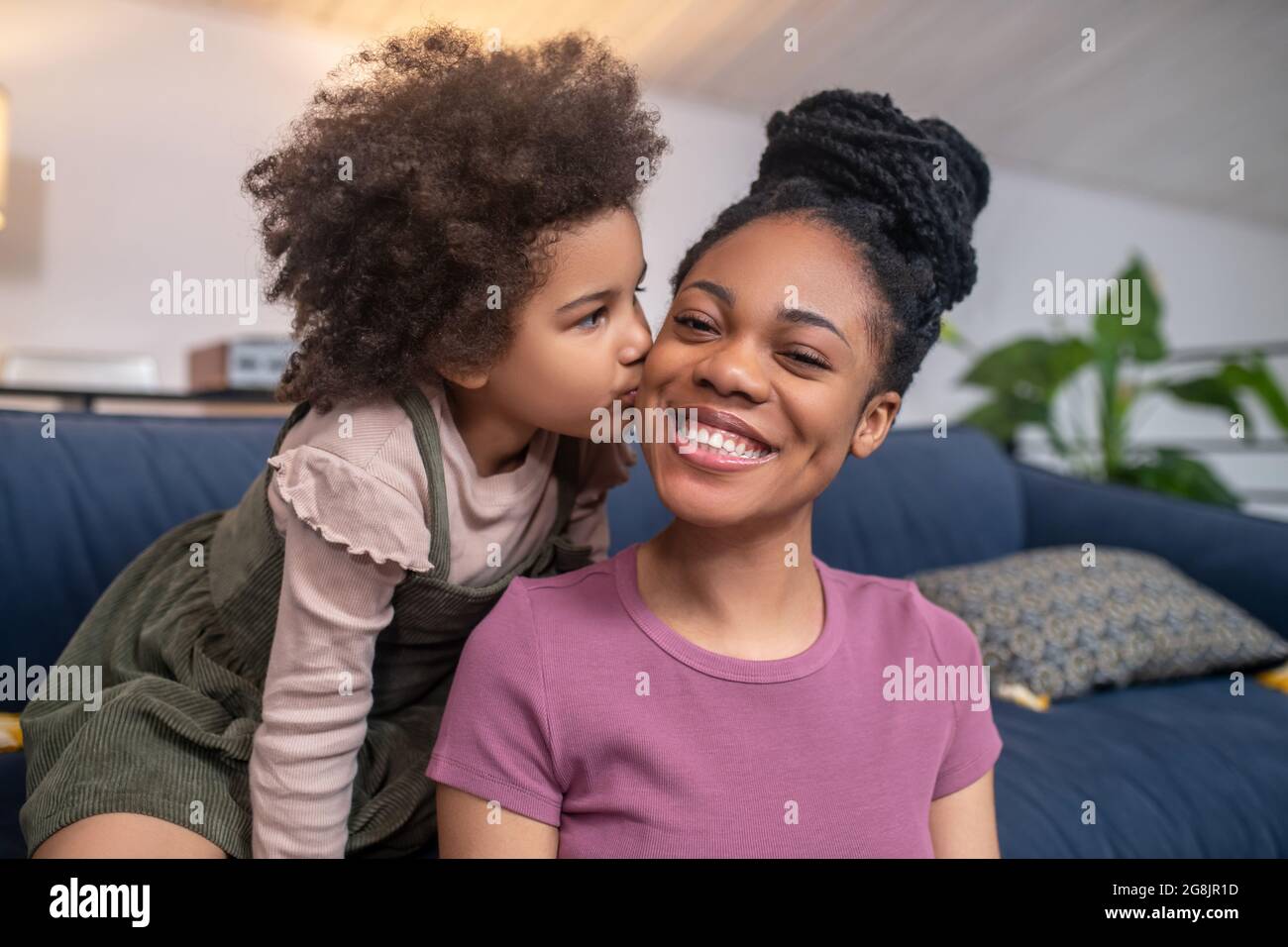 Petite fille embrassant maman heureuse sur joue Banque D'Images