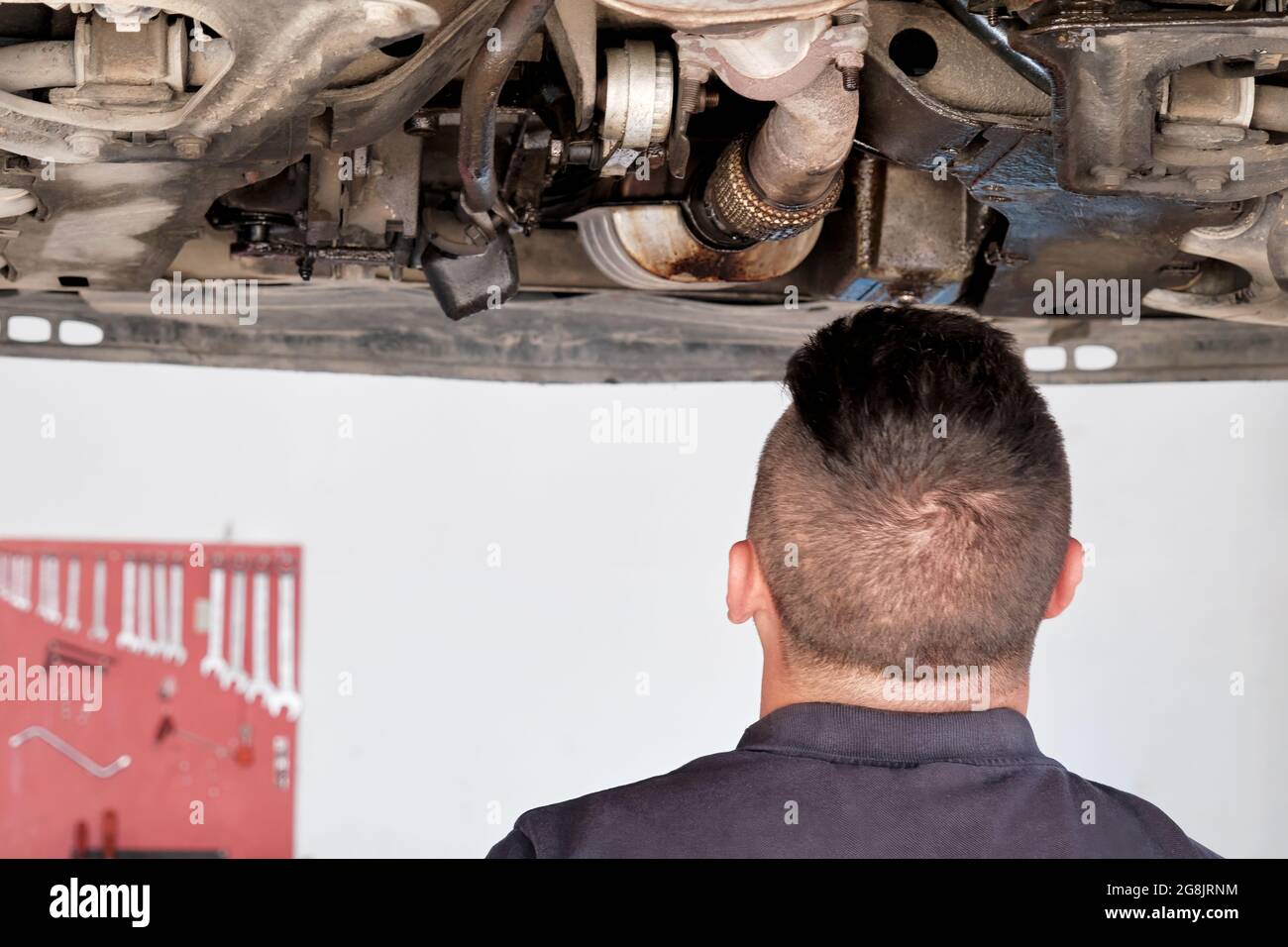 Un mécanicien vérifie une voiture soulevée au poste de réparation automobile. Banque D'Images
