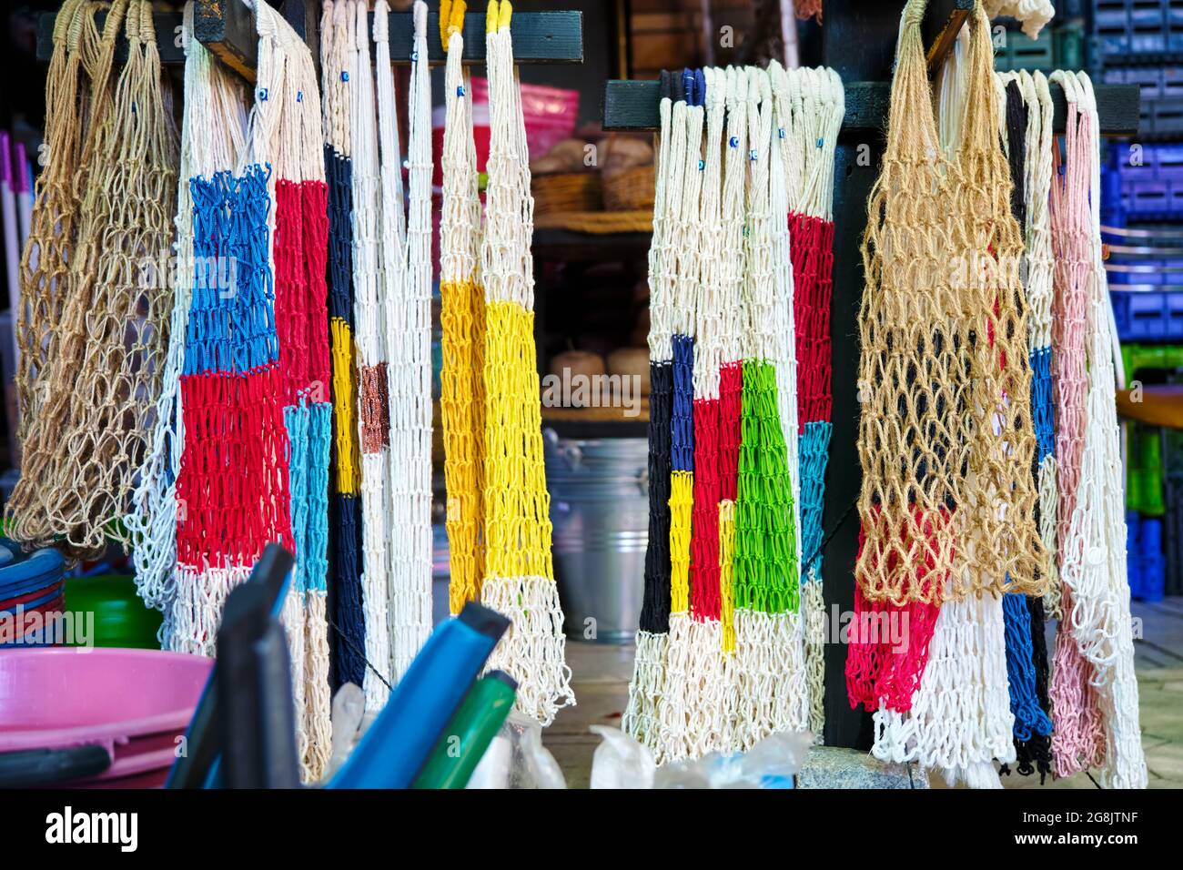 Sacs en maille de coton réutilisables colorés suspendus et présentés dans un magasin de sacs à provisions. Banque D'Images