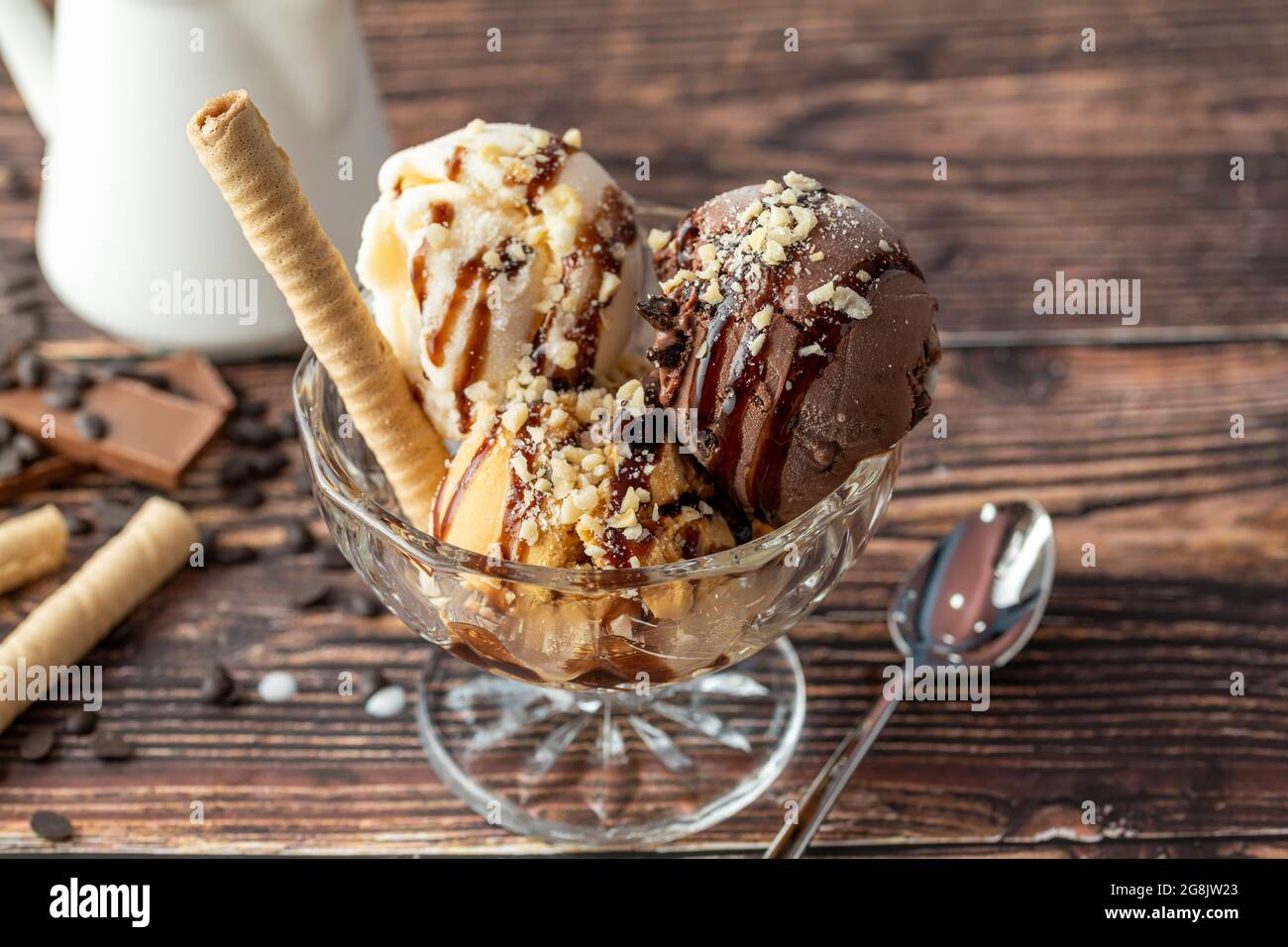 Glace Roma au chocolat, à la crème et au caramel dans un bol en verre avec une sauce au chocolat et aux noisettes. Banque D'Images