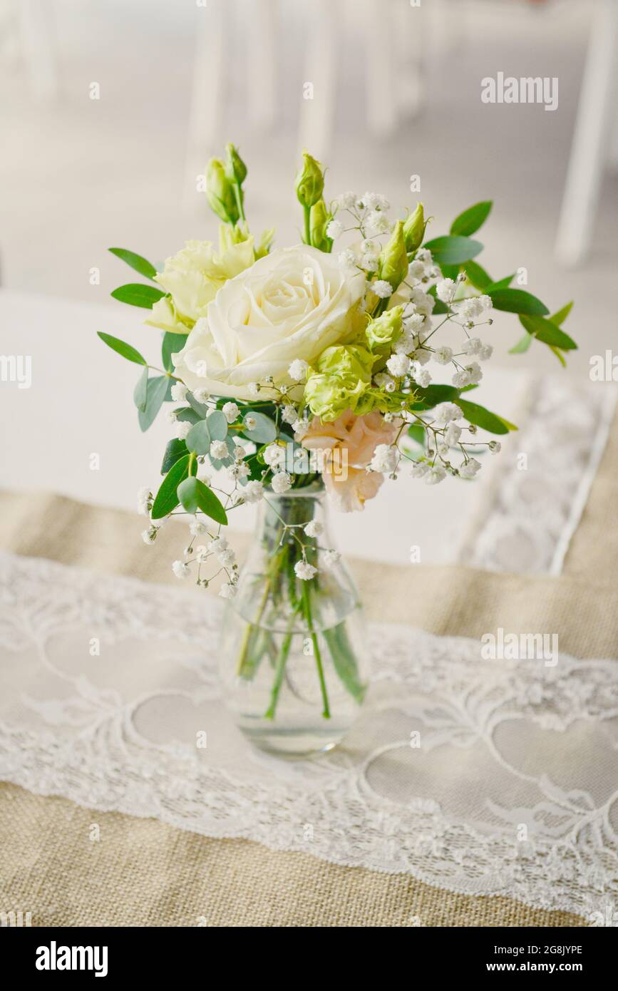 Un petit bouquet de fleurs avec une rose blanche dans un vase transparent  sur une table de cérémonie de mariage Photo Stock - Alamy