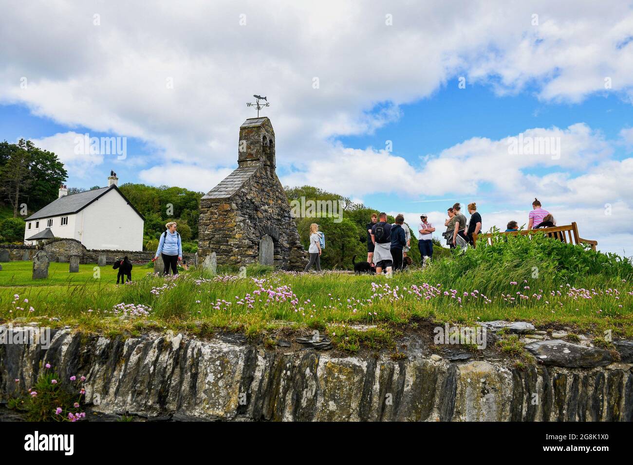 Les gens visitent les ruines de l'église dans la pittoresque MCG-yr-Eglwys, Pembrokeshire, au sud du pays de Galles. Il a été signalé que le petit village de bord de mer a plus de maisons de vacances que les résidents permanents avec des locaux étant hors prix du marché de la propriété. Seulement deux des cinquante propriétés du village abritent maintenant des locaux. Banque D'Images