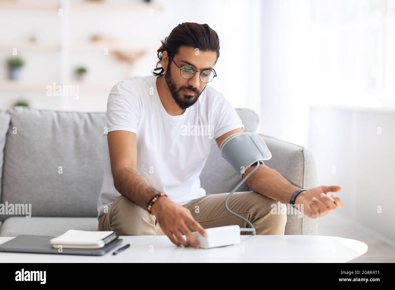 Homme assis vérifiant la tension artérielle à la maison Banque D'Images