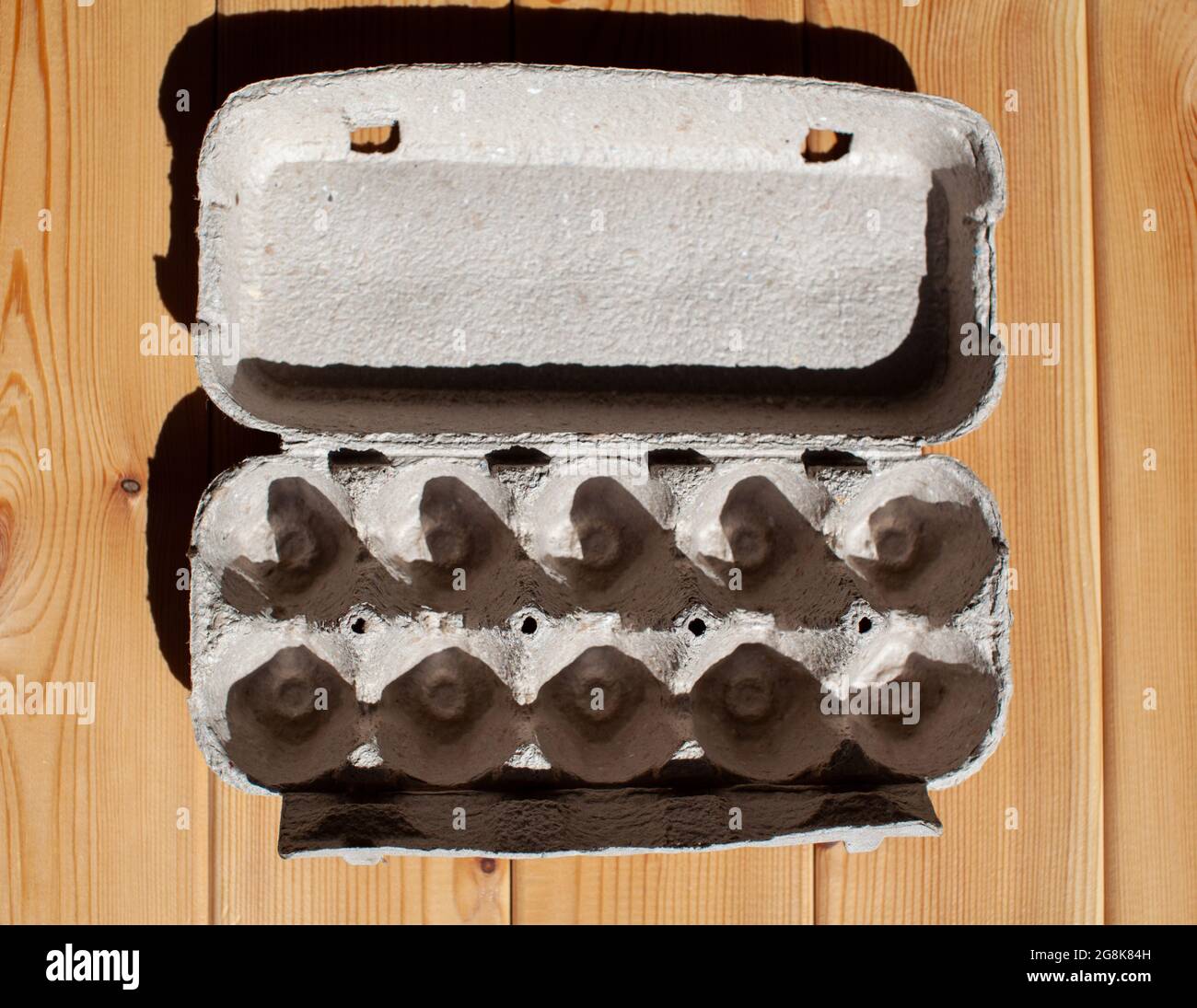 Carton gris à œufs sans œufs sur fond blanc. Boîte en carton à œufs en papier recyclé avec motif abstrait répété Banque D'Images