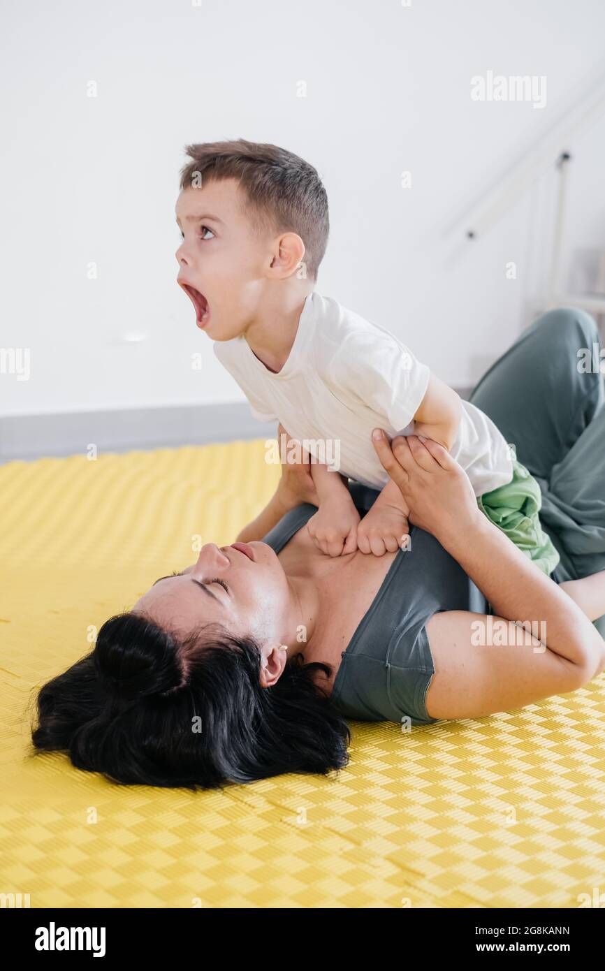 Réadaptation de l'enfant avec paralysie cérébrale dans un centre spécial. Mère faisant des exercices physiques et jouant avec joie avec garçon, activités sportives pour Banque D'Images