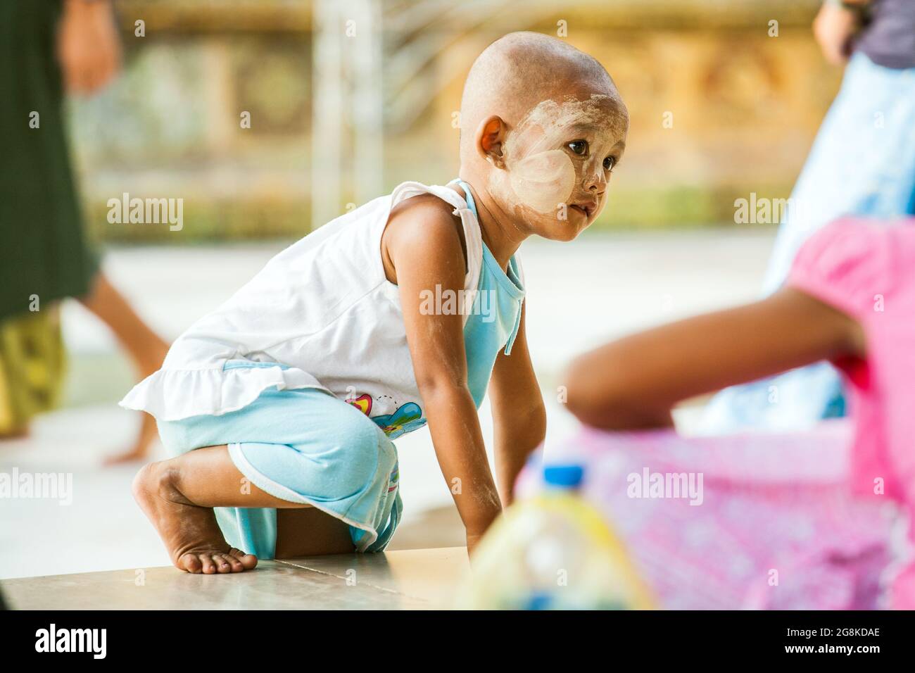 Un jeune enfant birman au visage hanaka et à la tête rasée monte sur le mur, Pagode Shwedagon, Yangon, Myanmar Banque D'Images