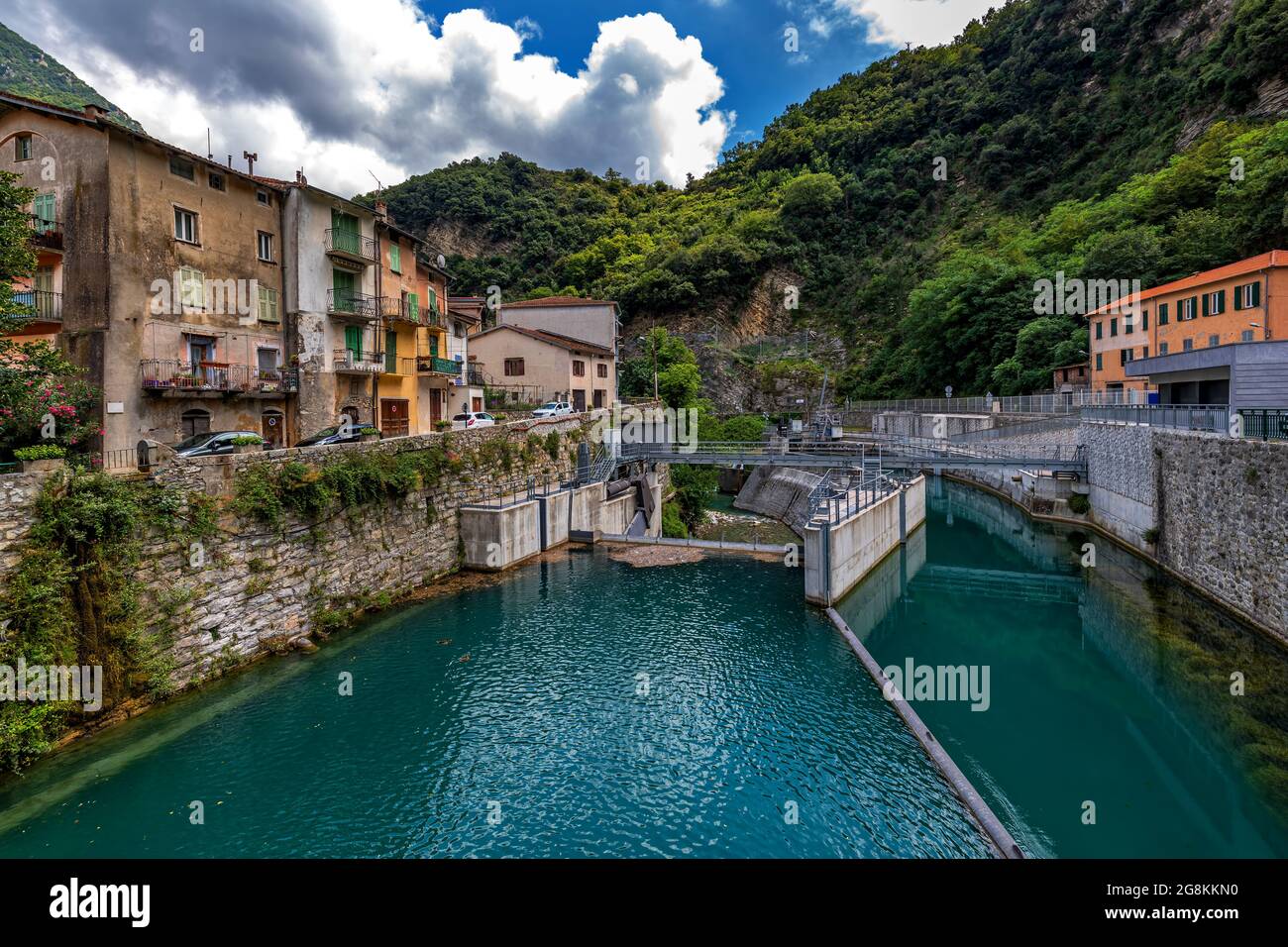 Vue sur les vieilles maisons, le barrage et l'eau dans le réservoir dans la petite ville alpine de Breil sur Roya en France. Banque D'Images